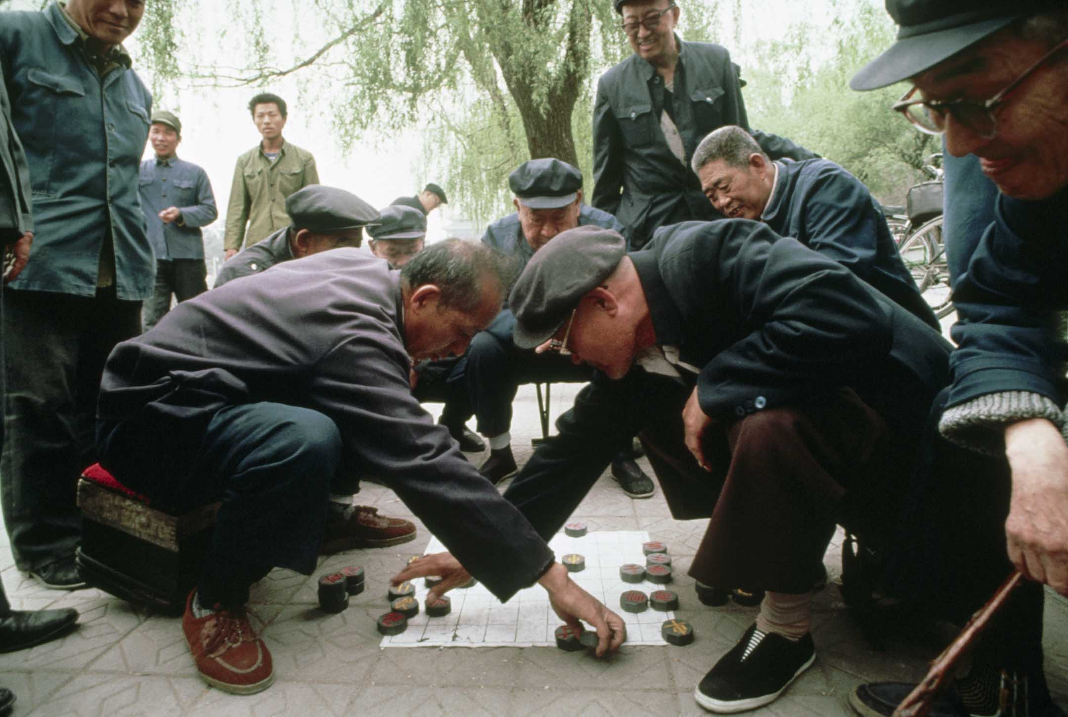 1989年4月日，北京的一个公园里，一群人围著两个下象棋的男人。 欧洲象棋就是源于这种古老的游戏。摄： Turnley/Corbis/VCG via Getty Images