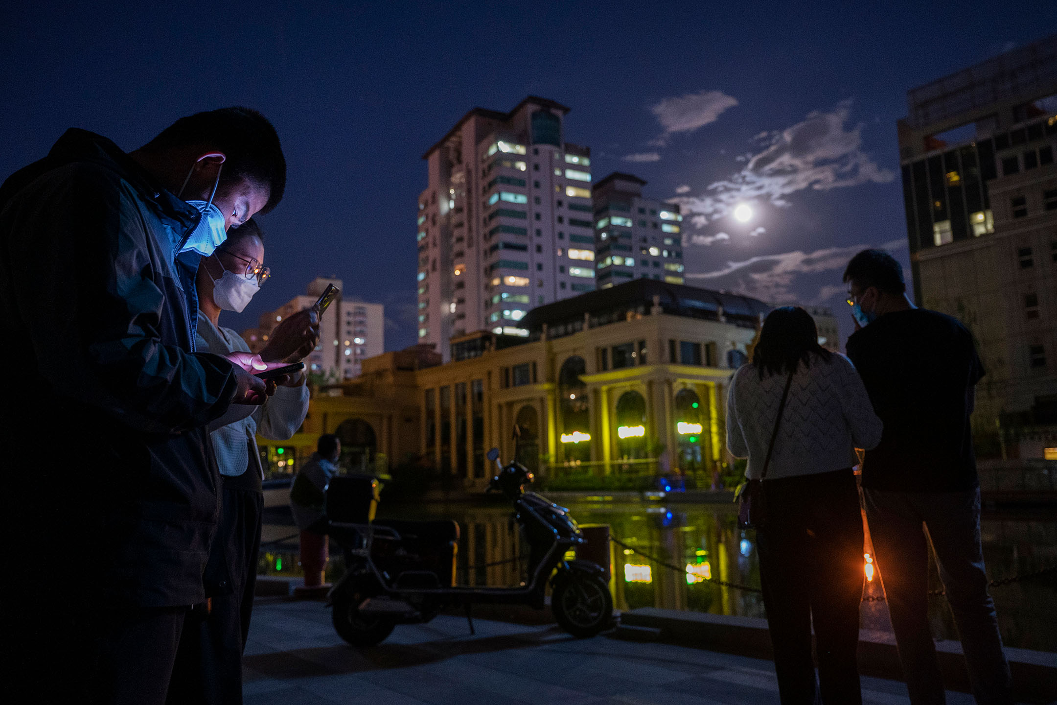 2022年5月15日，中国北京，疫情防控期间，市民在街道上看手机。摄：Kevin Frayer/Getty Images