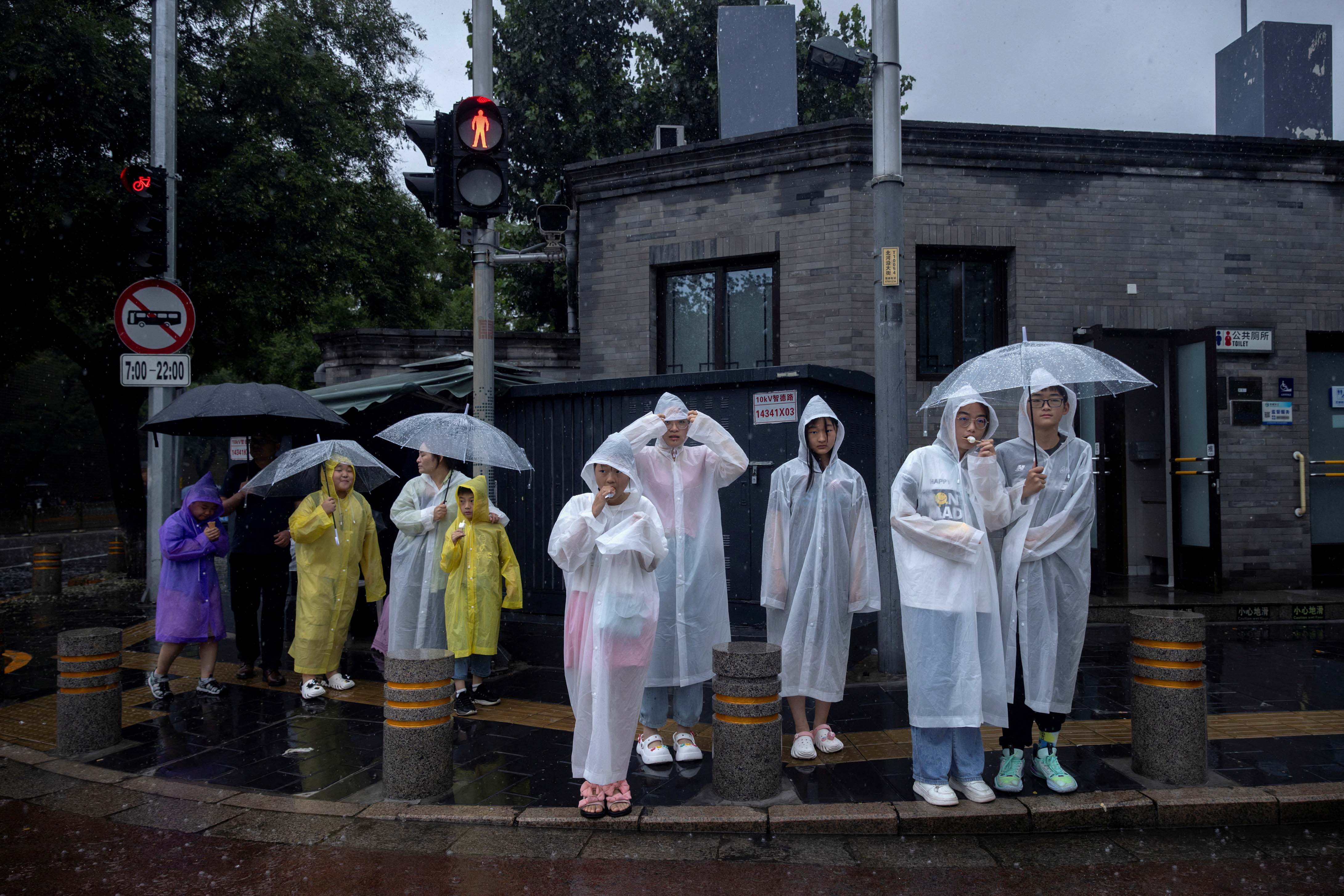 2023年7月30日，北京，旅游区内的人们穿著雨衣。摄：Thomas Peter/Reuters/达志影像