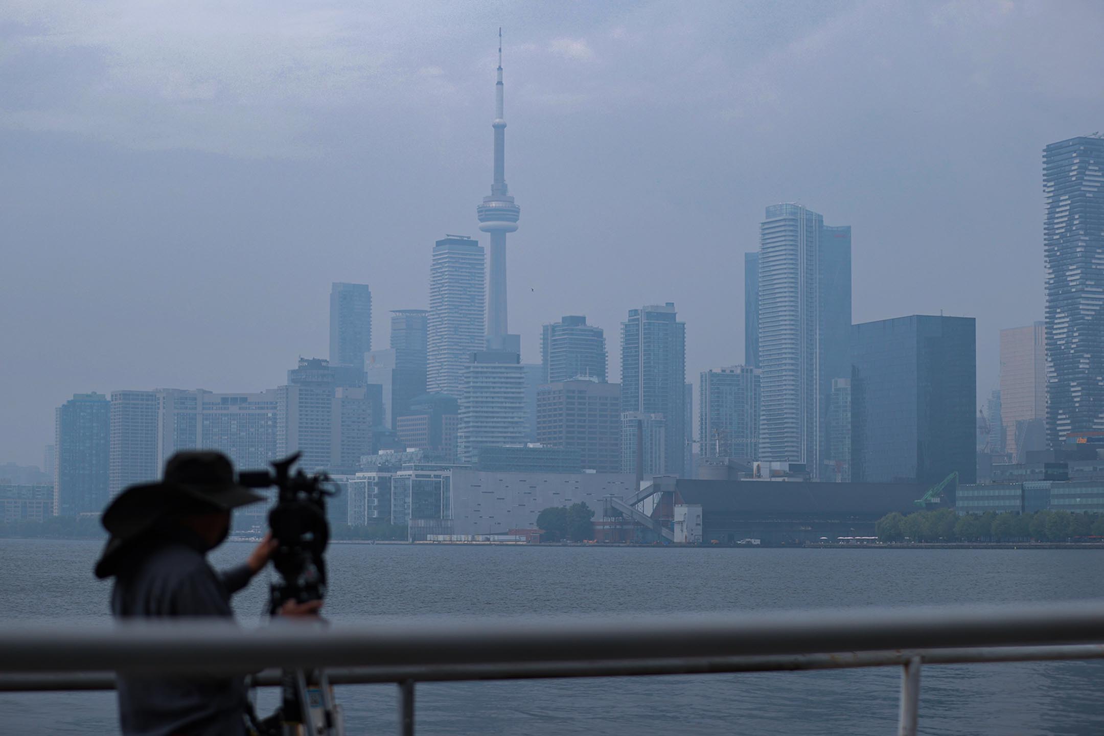 2023年6月30日，一名记者拍摄多伦多朦胧的天际线。摄：Lance McMillan/Toronto Star via Getty Images