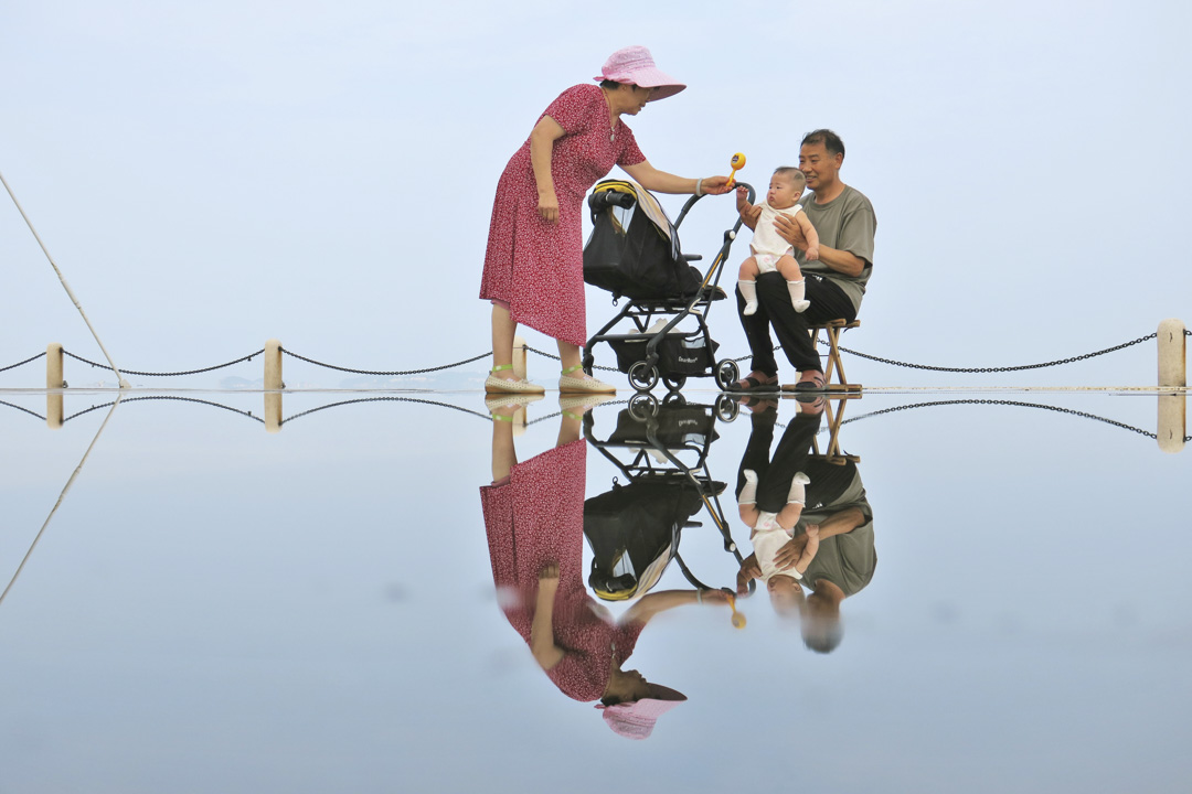 2022年7月29日，中国山东省烟台市，一对老夫妇在逗孙子。摄：Tang Ke/VCG via Getty Images