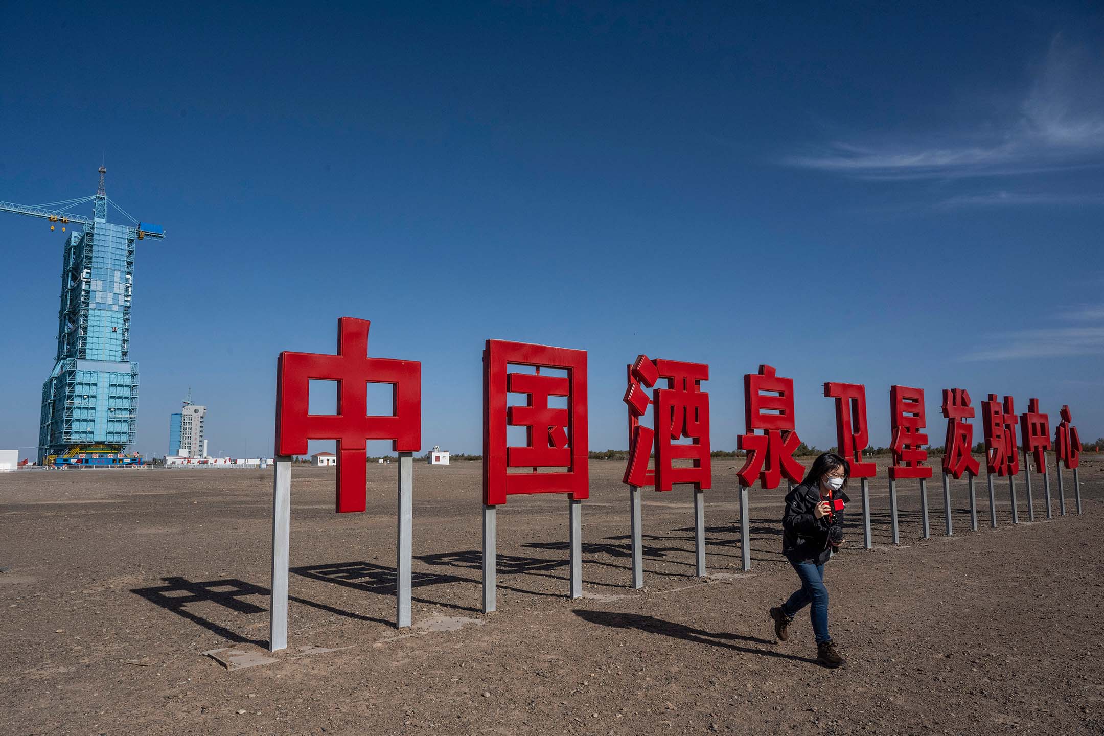 2021年10月15日，中国酒泉，一名记者在酒泉卫星发射中心的神舟十三号发射台旁。摄：Kevin Frayer/Getty Images