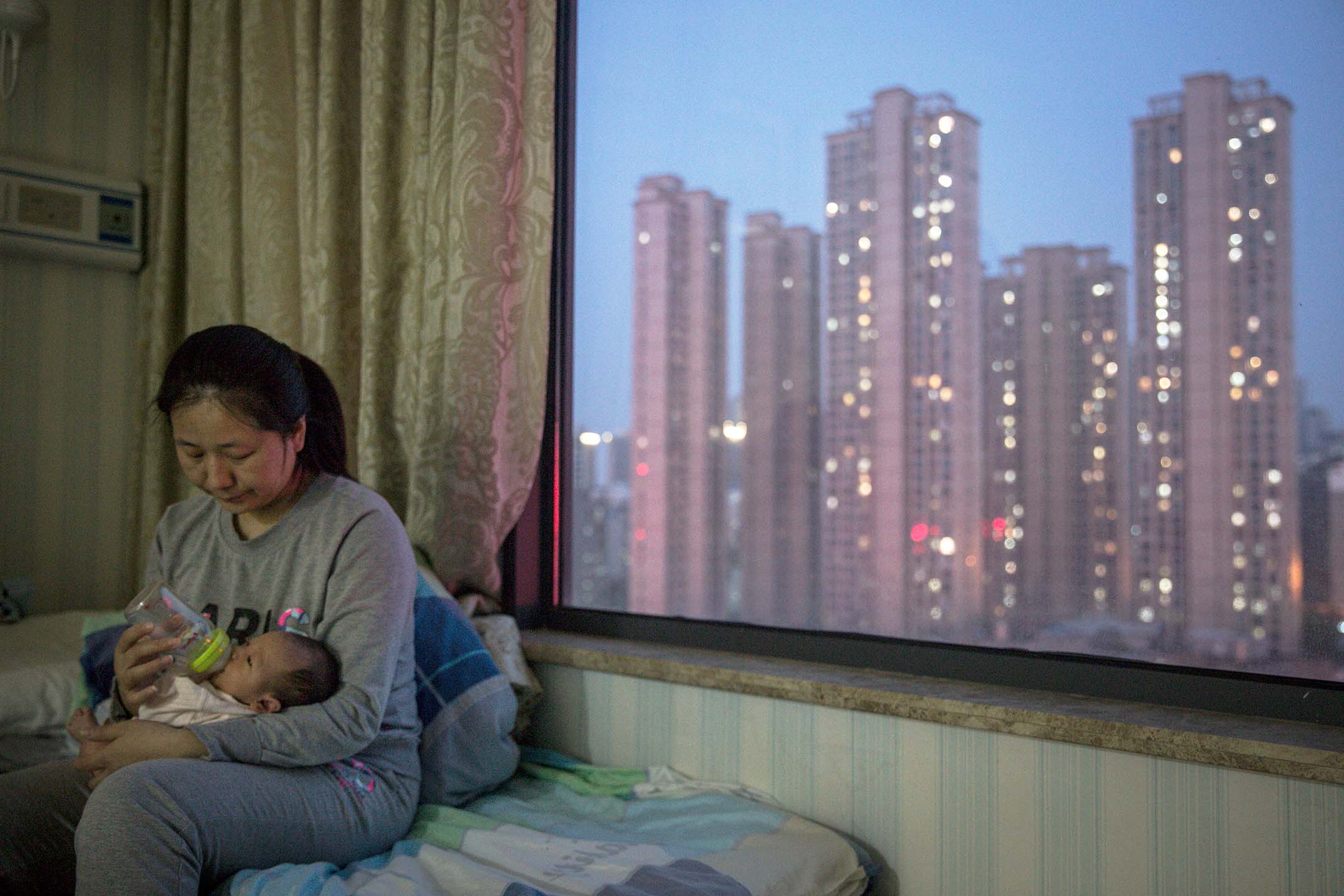 2020年3月12日，中国武汉，一名护士在窗前为新生儿喂奶。摄：Stringer/Getty Images