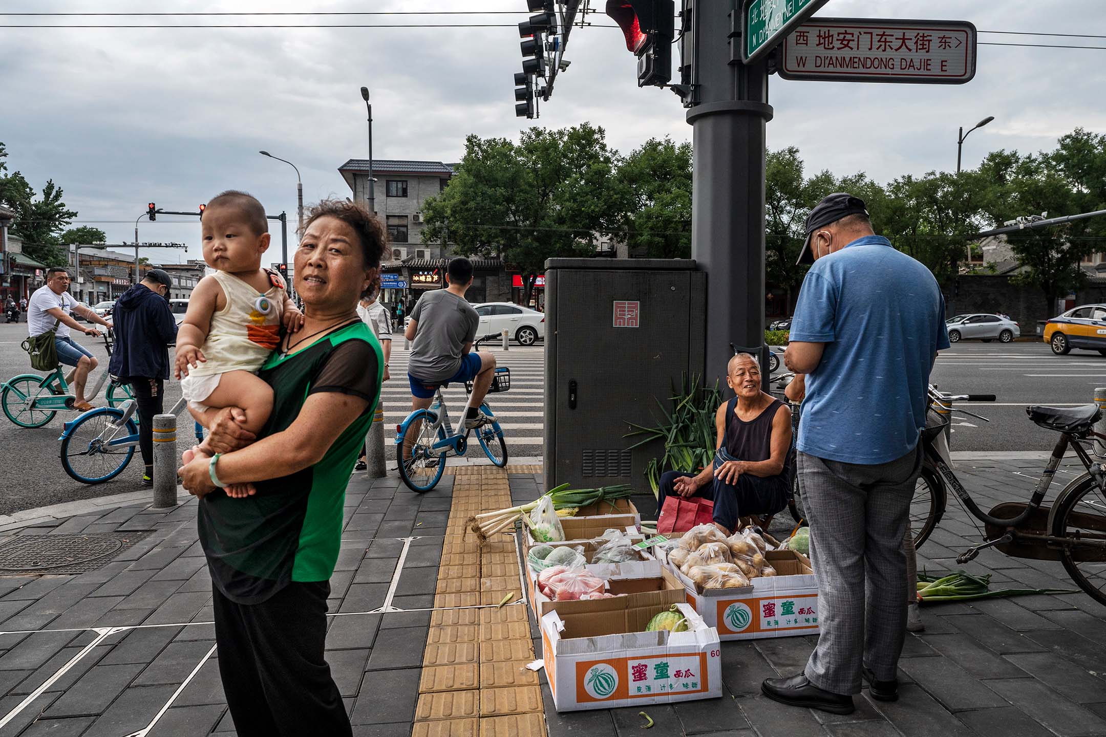 2022年6月28日，中国北京， 一名女子站在街头上抱著孩子。摄：Kevin Frayer/Getty Images