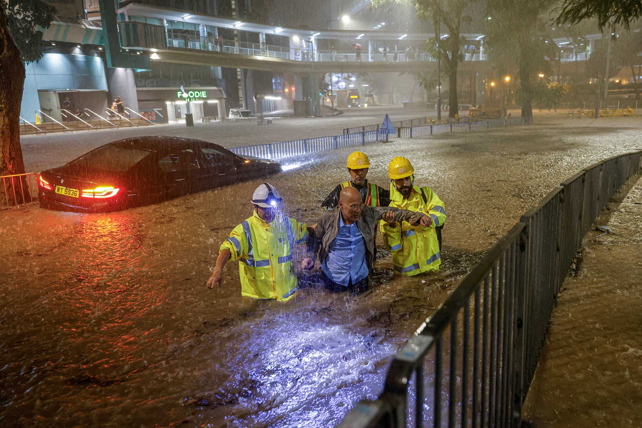 2023年9月8日，香港，大雨下，管理排水系统的人员协助一名因洪水被困的司机前往安全地点。摄：Tyrone Siu/Reuters/达志影像