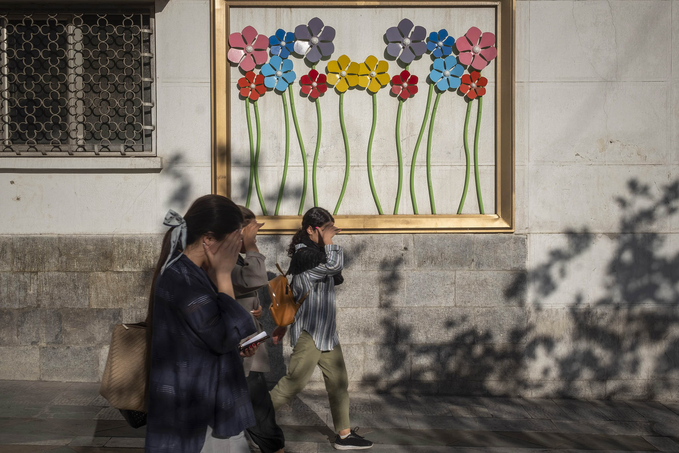 2023年9月12日，伊朗女生遮著脸沿著德黑兰市中心的一条大道行走。摄：Morteza Nikoubazl/NurPhoto via Getty Images