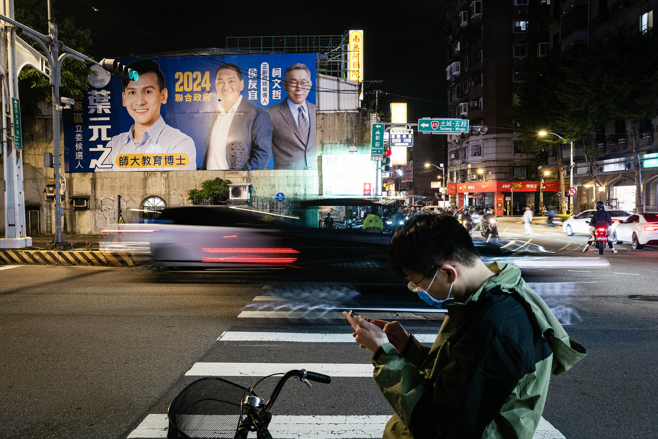 2023年10月25日，板桥，一名国民党立委候选人在广告板上印上柯文哲和侯友宜的肖像。摄：陈焯辉/端传媒