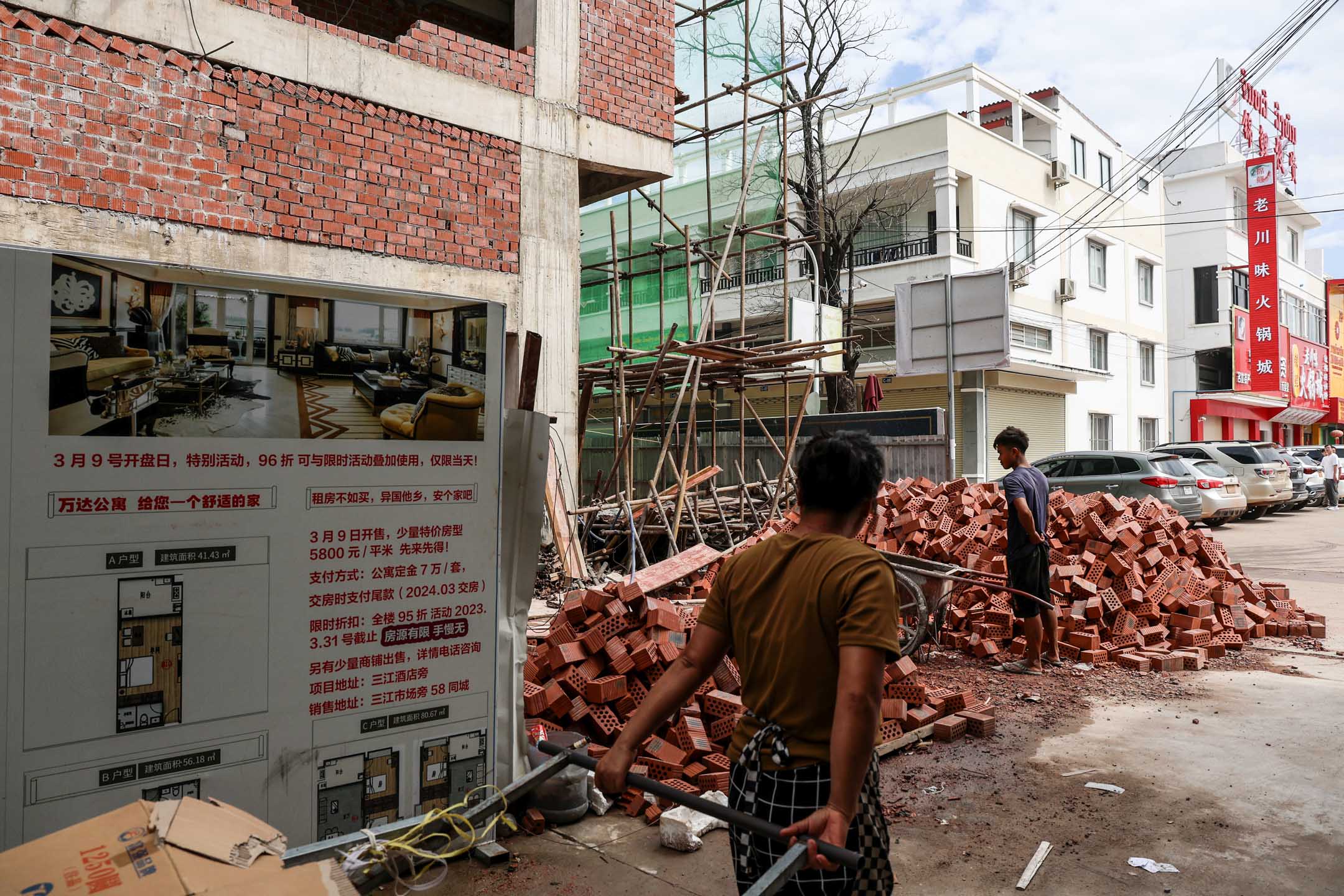 2023年6月24日，老挝万象，当地市场的建筑工地，工人们推着独轮车。摄：Valeria Mongelli/Bloomberg via Getty Images