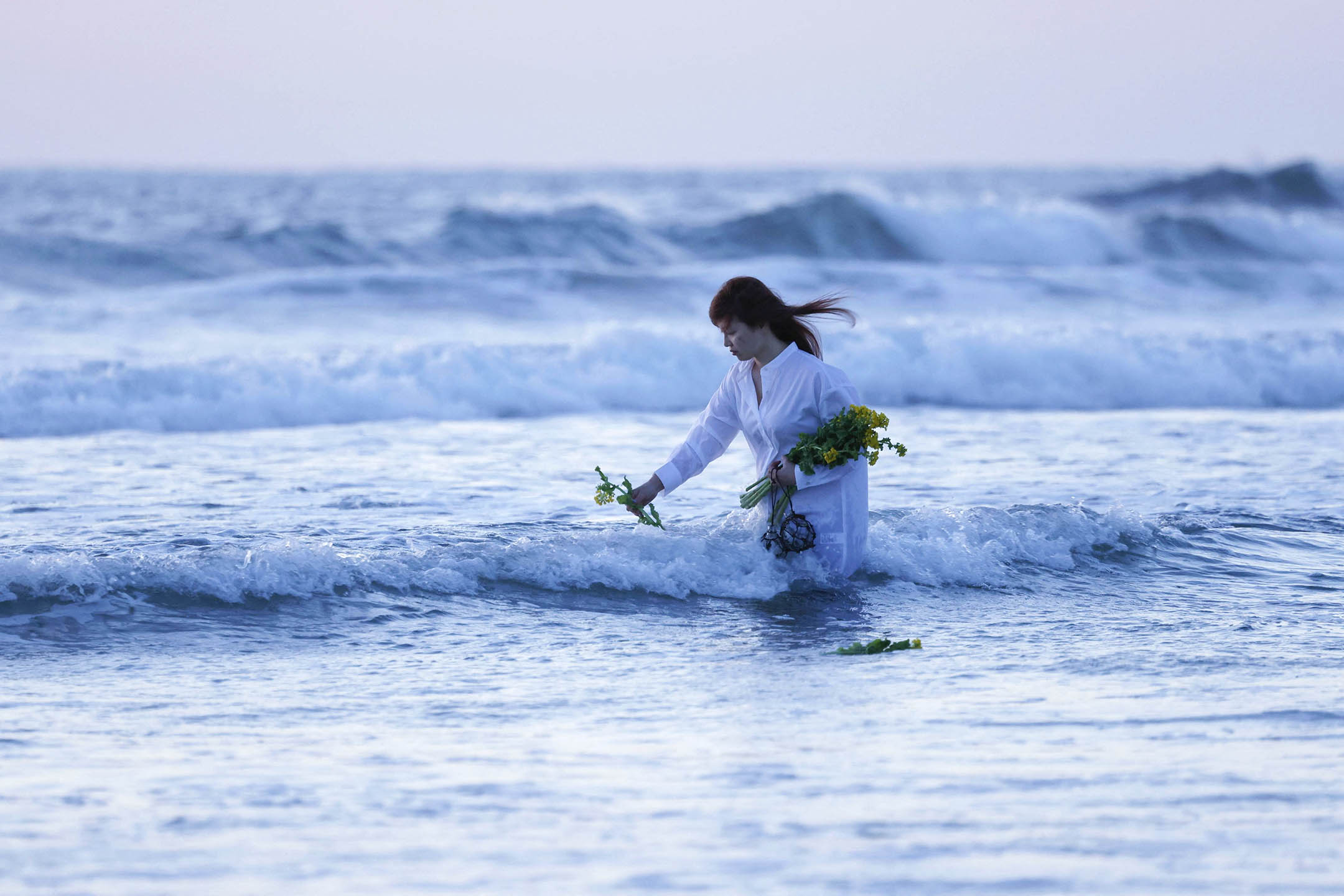 2023年3月11日，福島縣磐城市的海灘上，一名婦女在311地震的災區獻花，哀悼死者。攝： Kyodo via Reuters/達志影像