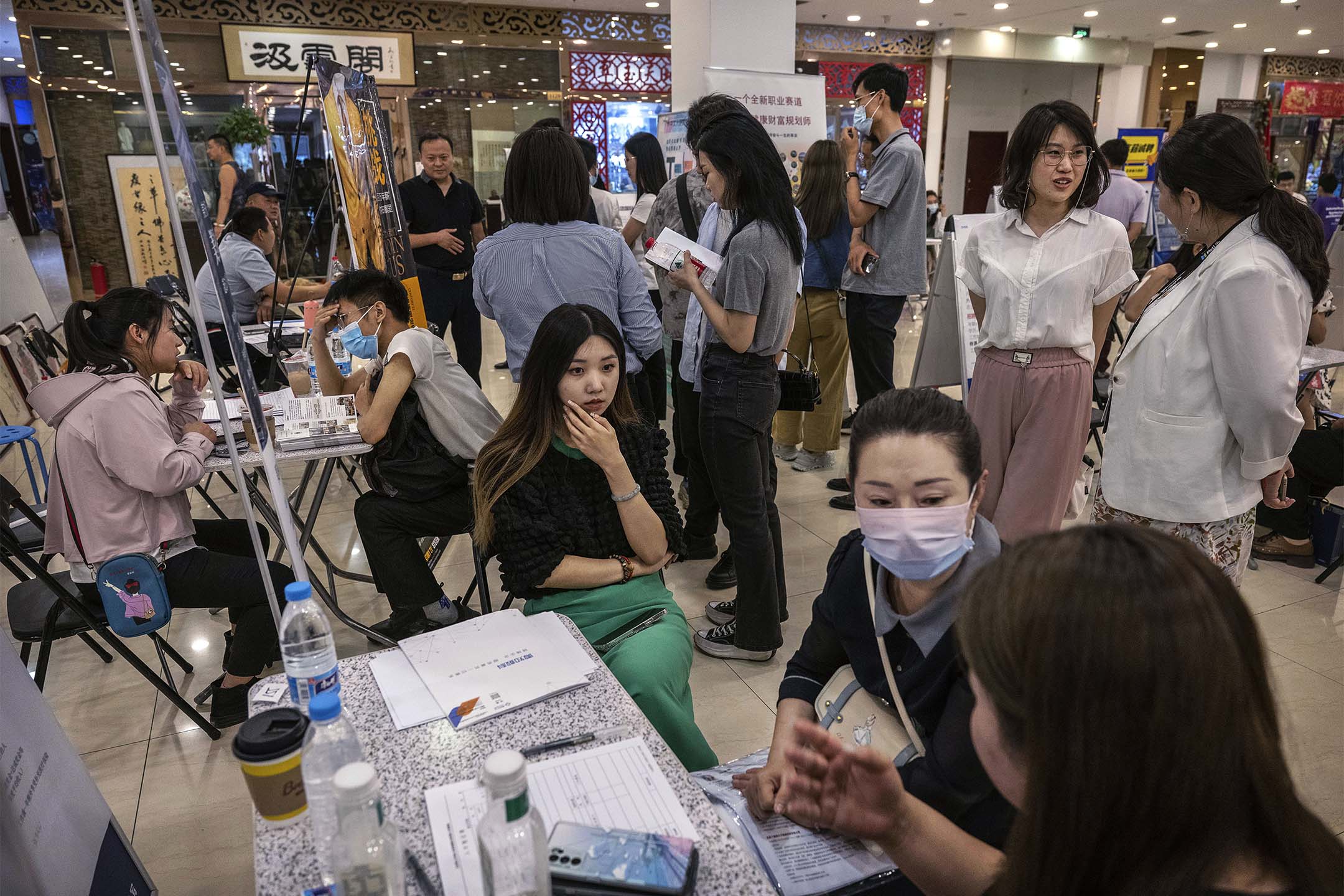 2023年6月9日，北京举行的招聘会上，求职者和招募人员交谈。摄：Kevin Frayer/Getty Images