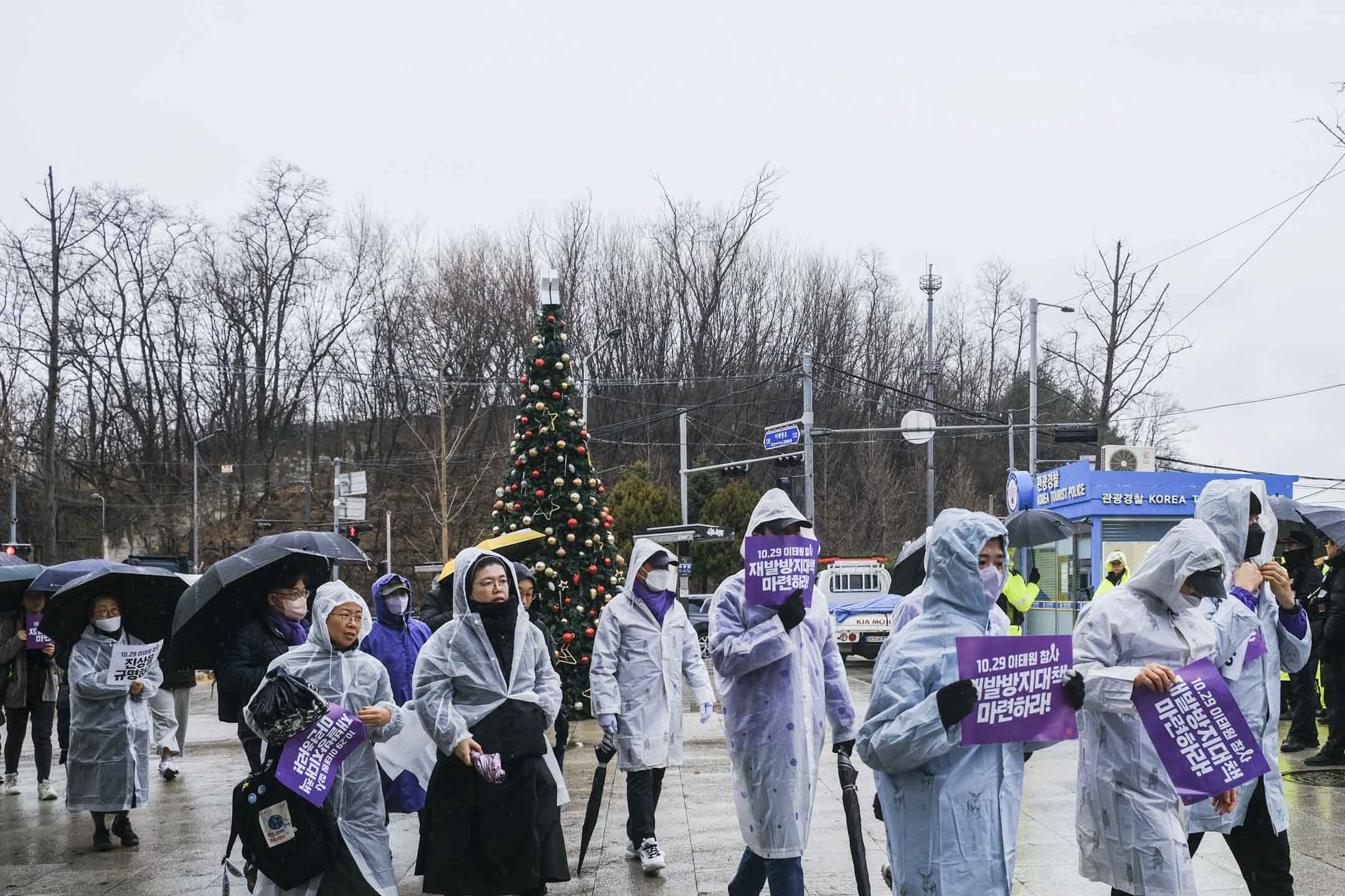 2023年12月14日，天下起大雨，遗属在绿莎坪站广场出发，徒步跨过汉江桥，游行到对岸的国会大楼。摄：余美霞/端传媒