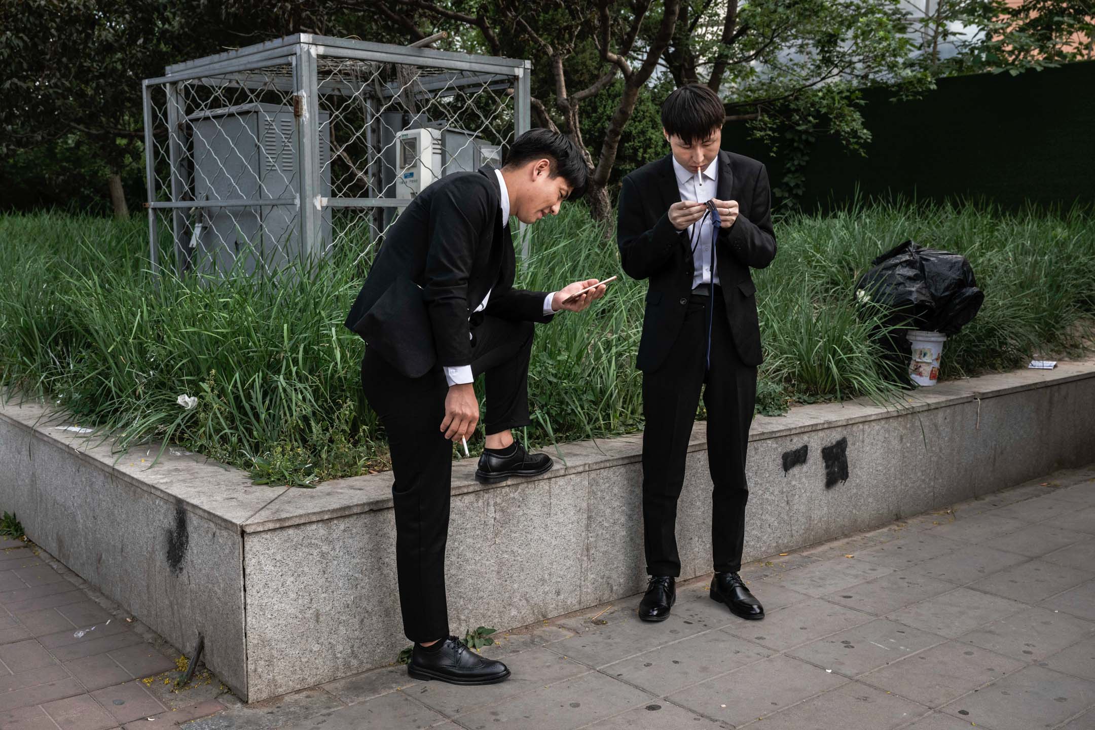 2023年6月7日，中国北京，两名男子站在地铁站外等候。摄：Kevin Frayer/Getty Images