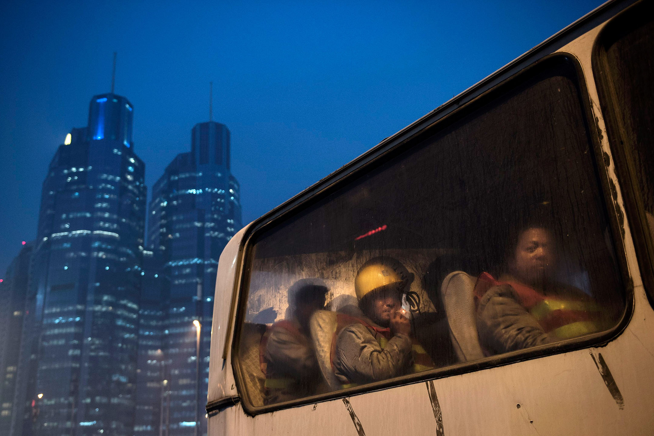 2014年12月9日，中国北京，建筑工人下班后乘坐公车离开。摄：Kevin Frayer/Getty Images