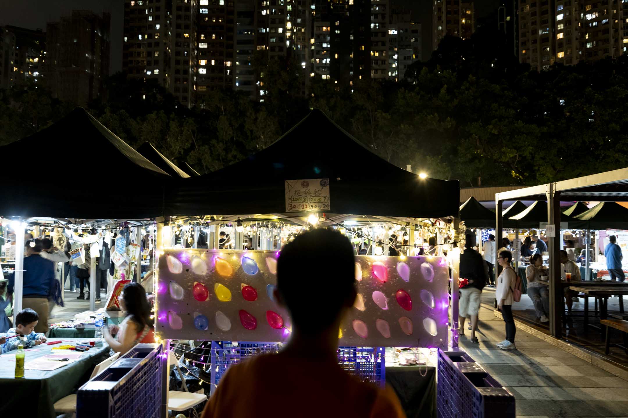 香港一名少年站在夜市中。摄：林振东/端传媒