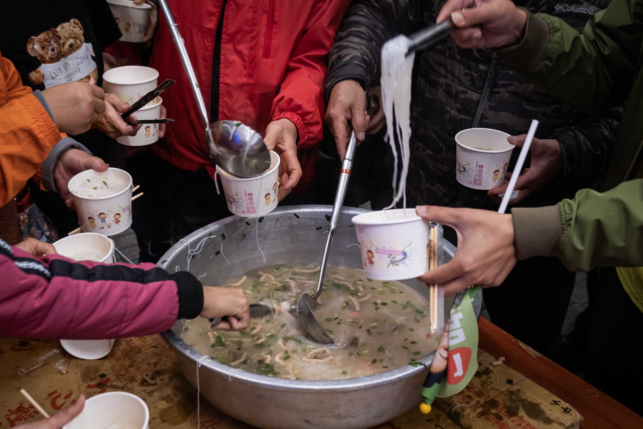 2023年12月26日，新北市，民进党立委候选人吴峥参香拜票，宫庙内的民众一起吃米粉等食物。摄：陈焯煇/端传媒