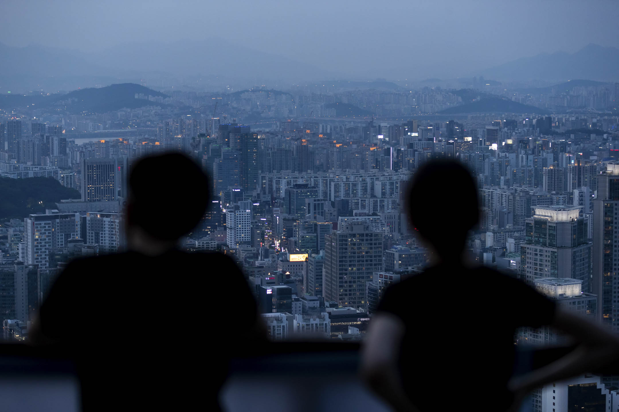 2020年7月9日，韩国首尔黄昏时分，人们眺望城市天际线。摄：SeongJoon Cho/Bloomberg via Getty Images