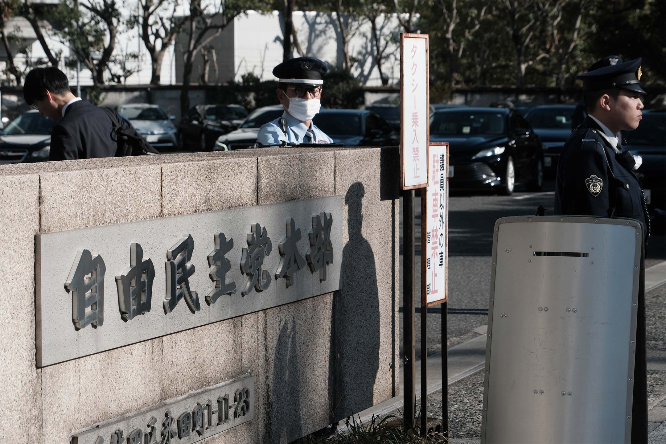 2023年12月14日，日本东京，警察站在自民党总部外。摄：Soichiro Koriyama/Bloomberg via Getty Images