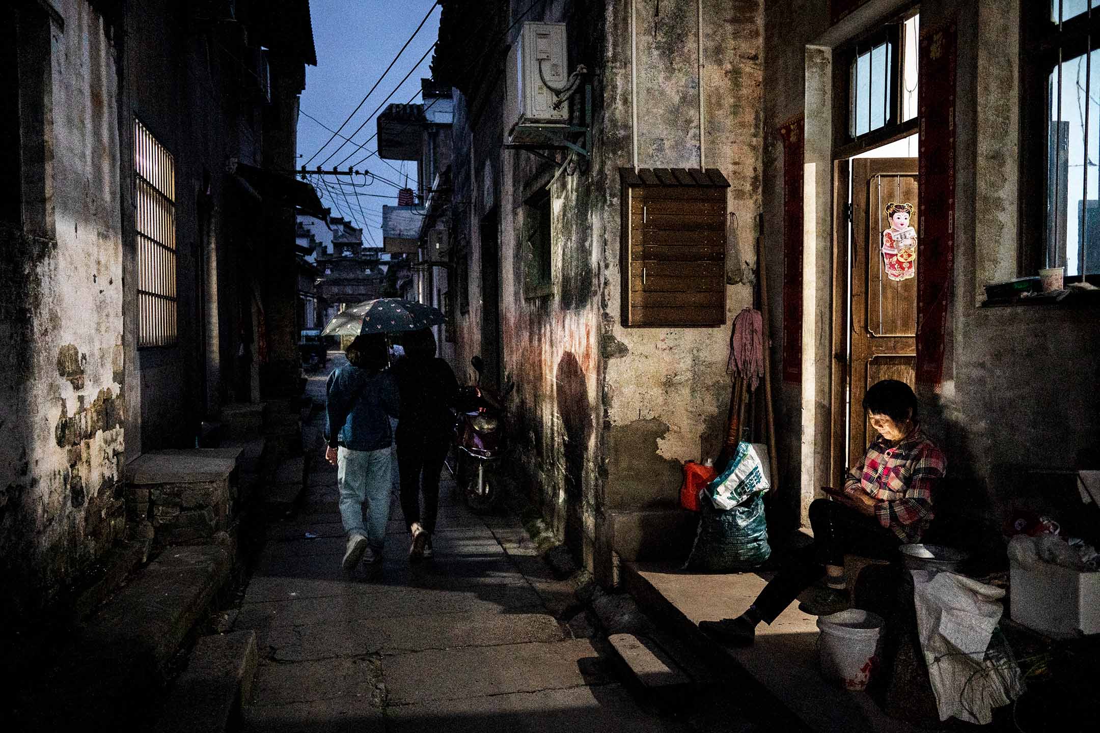 2023年5月10日，中國安徽省，一名女士坐在房子外看手機。攝：Kevin Frayer/Getty Images