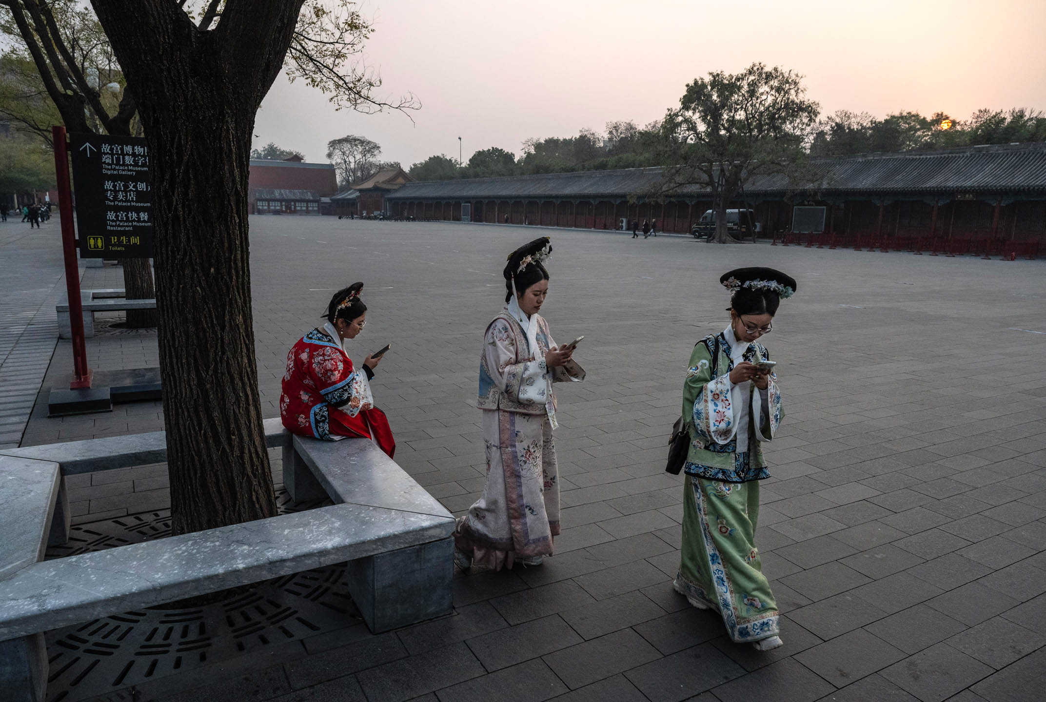 2023年11月21日，中国北京，游客身穿传统汉服看手机。摄：Kevin Frayer/Getty Images