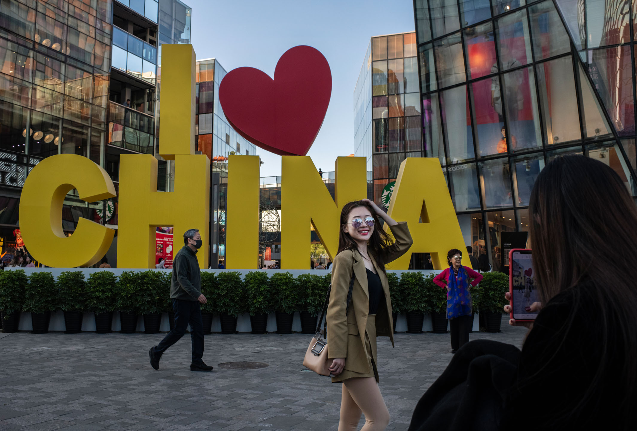 2019年10月31日，中国北京，一名女士在购物中心外拍照。摄：Kevin Frayer/Getty Images