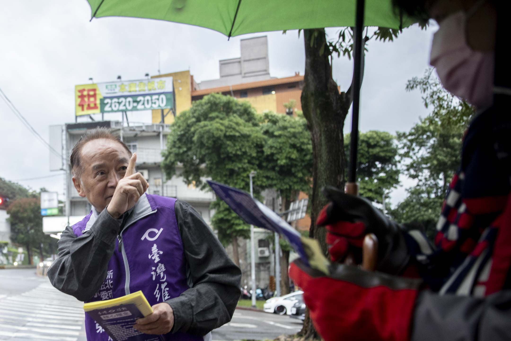 72岁的徐百弟是第一个在台湾参选区域立委的香港人，去年12月一个强烈寒流袭台的一天，徐百弟在雨中派选举单张。摄：林振东/端传媒