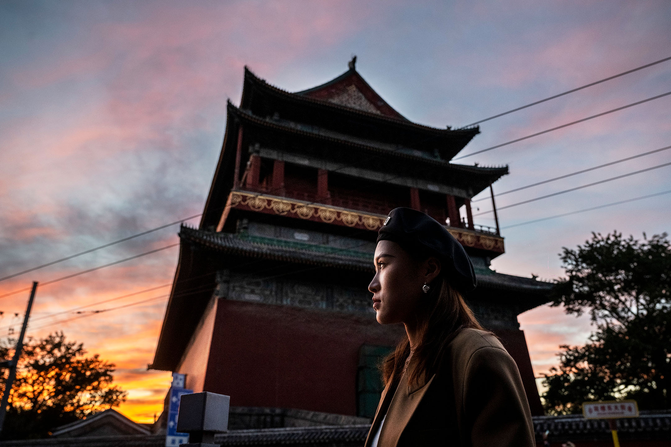 2021年10月10日，中國北京，日落時分，一名女士站在鼓樓附近。攝：Kevin Frayer/Getty Images