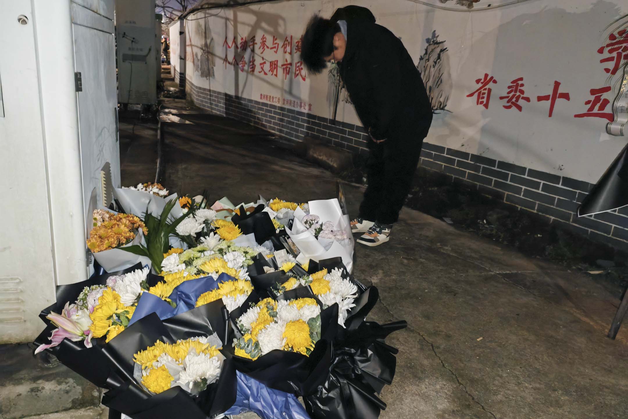 2024年1月25日，中国江西新余市一场大火导致39人死亡后，一名男子在火灾现场附近鞠躬哀悼罹难者。摄：VCG/VCG via Getty Images