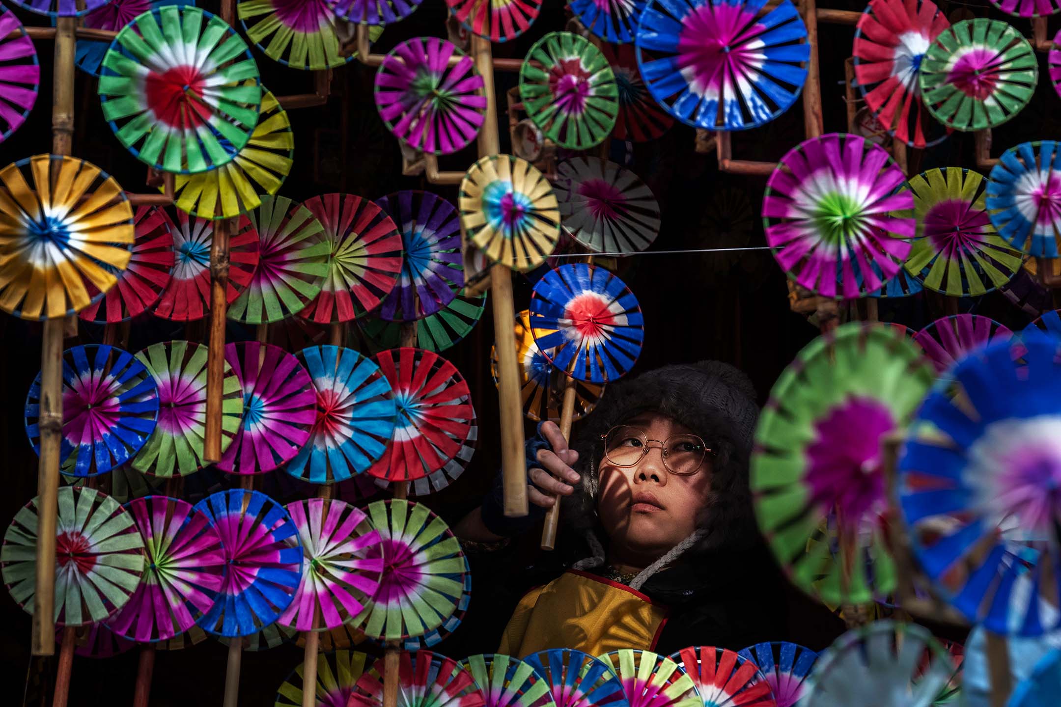 2024年2月13日，中国北京，一名女士正在看摆满风车的摊位。摄：Kevin Frayer/Getty Images