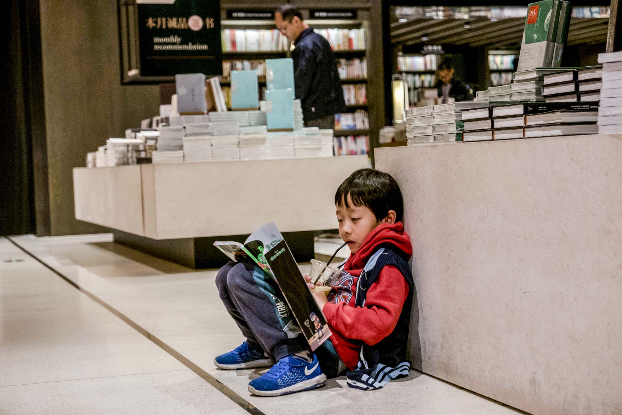 中国苏州一个小男孩坐在诚品书店的地板上读书。摄：Zhang Peng/LightRocket via Getty Images