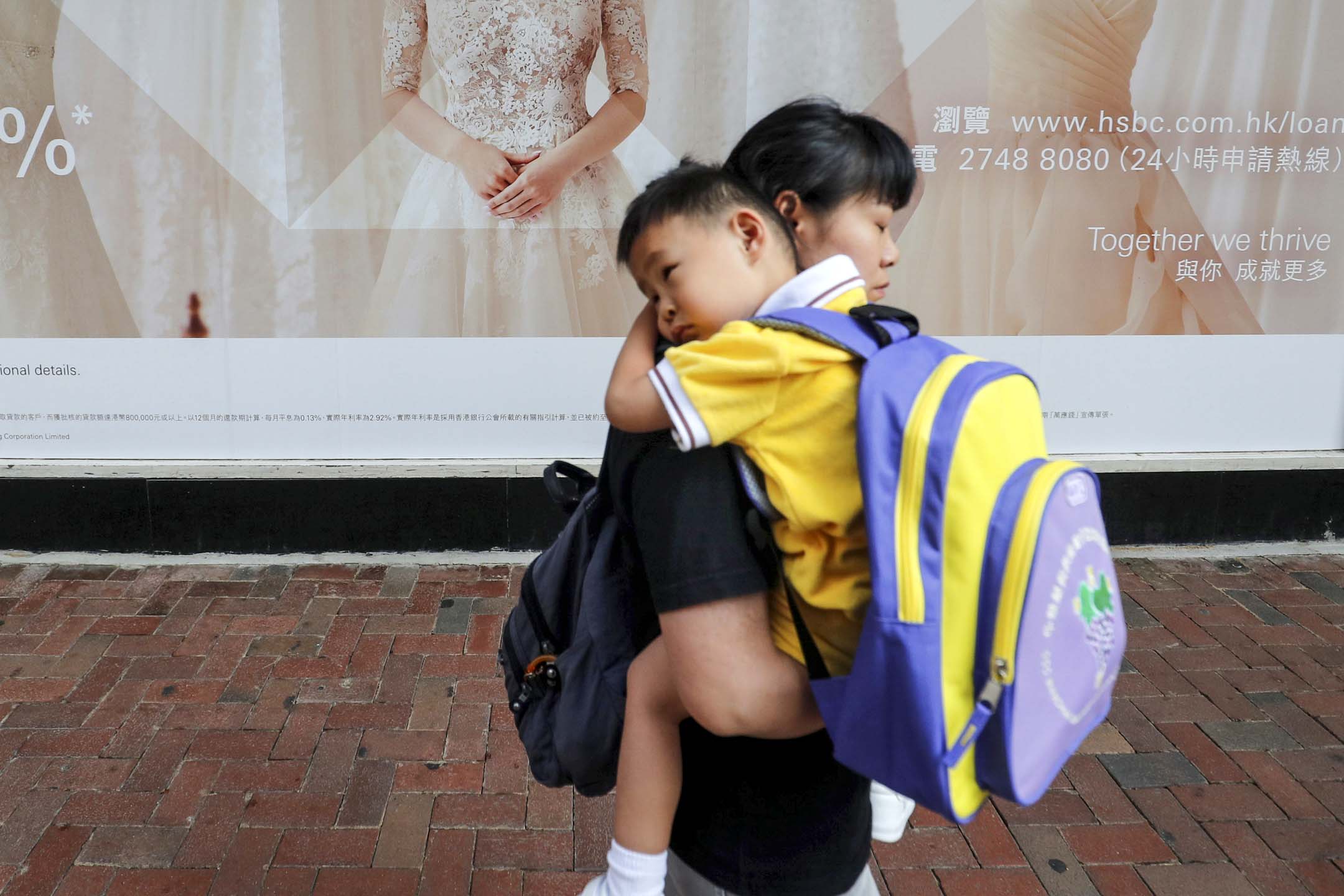 香港一位母亲抱著孩子上学。摄：Amr Abdallah Dalsh/Reuters/达志影像