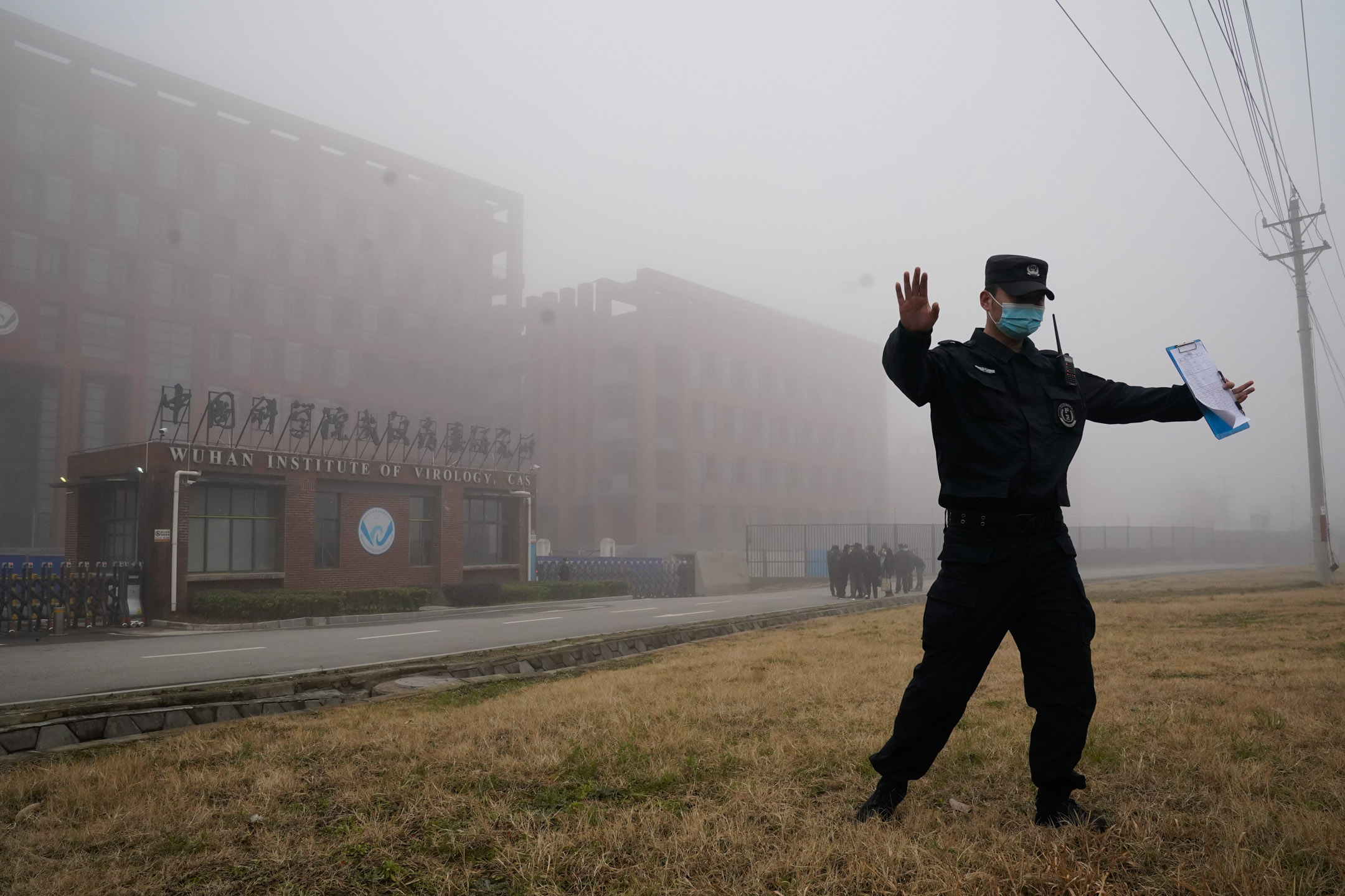 2021年2月3日，中国武汉，世界卫生组织团队抵达当地进行实地考察后，一名安全官员将记者带离武汉病毒学研究所。摄：Ng Han Guan/AP/达志影像