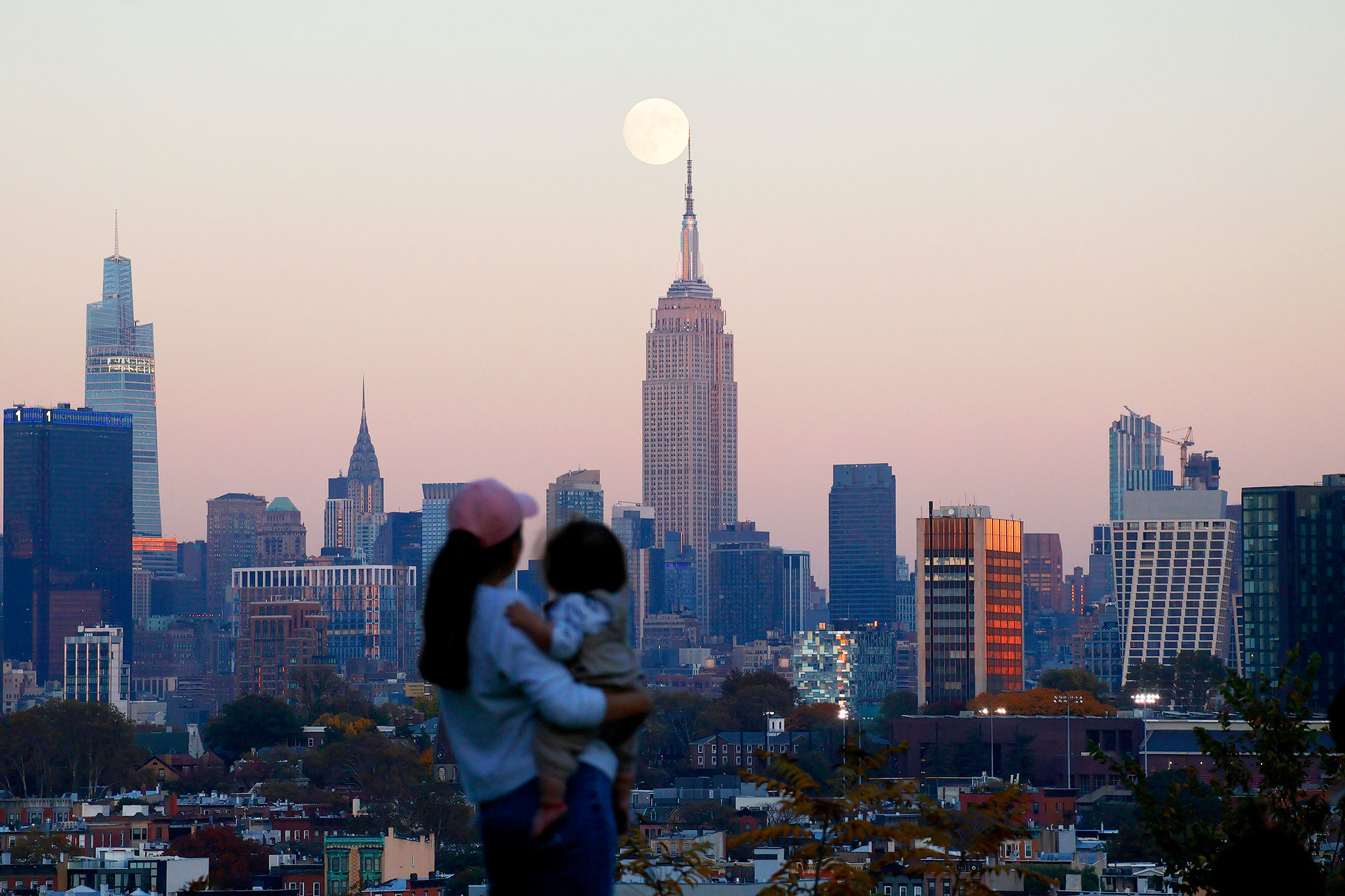 2023年10月27日，美國紐約，一名婦女看著月亮在城市後升起。攝：Gary Hershorn/Getty Images