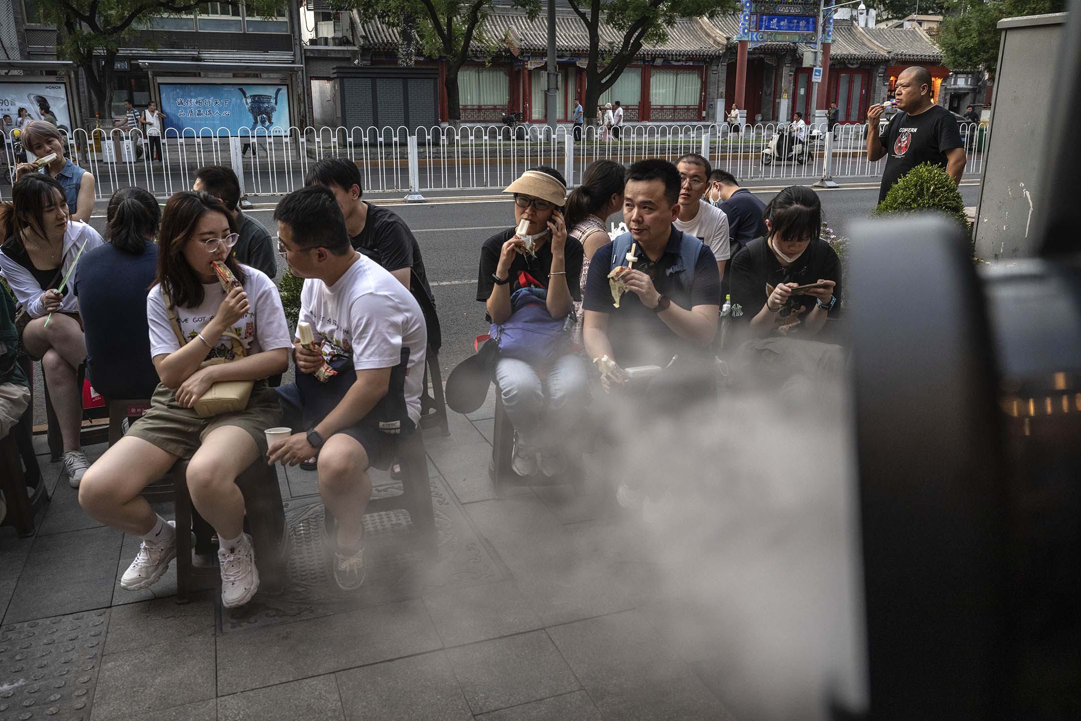 2023年6月23日，北京在熱浪期間，人們在當地一家受歡迎的餐廳外吃著餐廳工作人員提供的冰淇淋。攝：Kevin Frayer/Getty Images