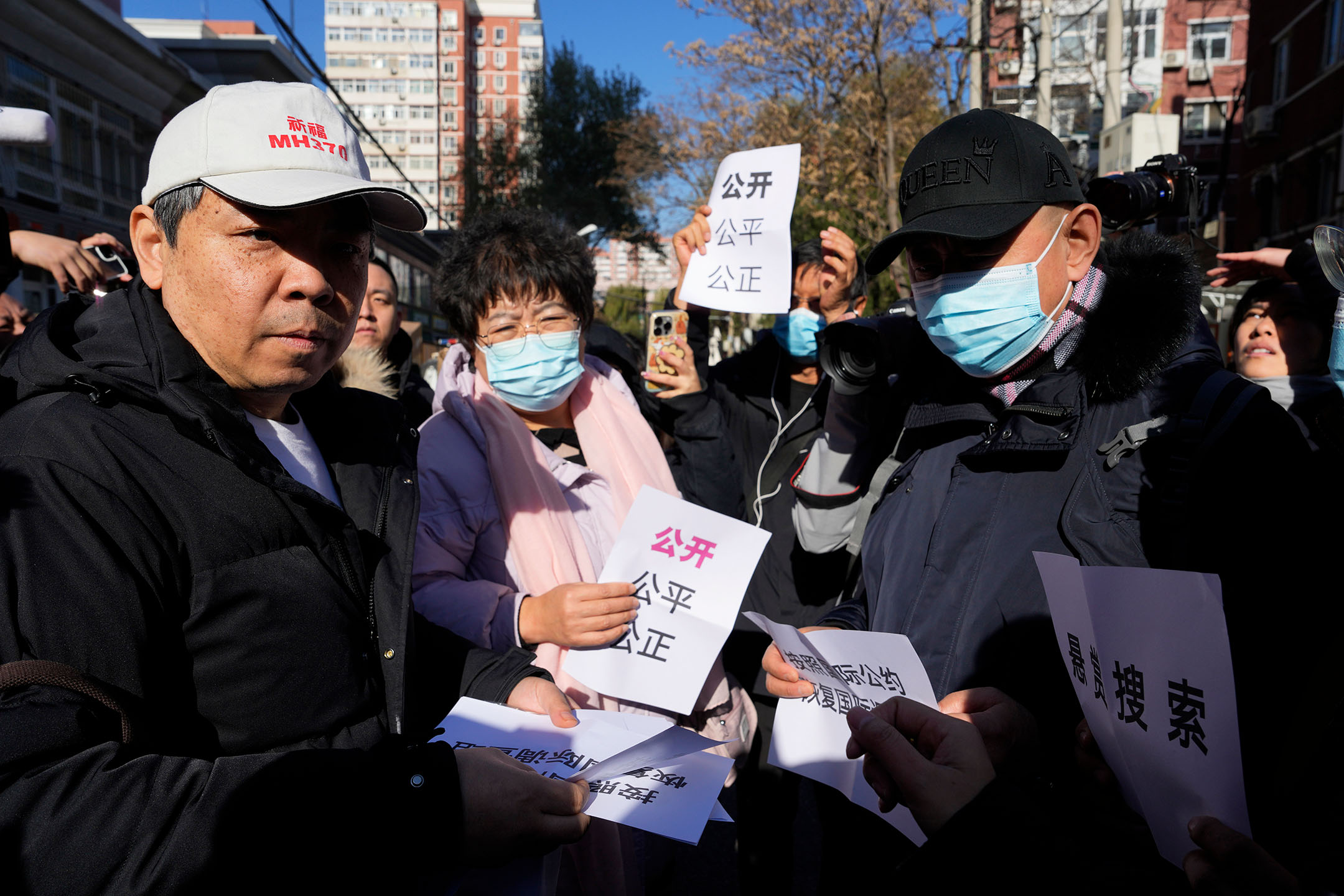 2023年2月27日，中国北京，马航370客机乘客亲属分发写有“公开、公平、公正”字样的纸条。摄：Ng Han Guan/AP/达志影像