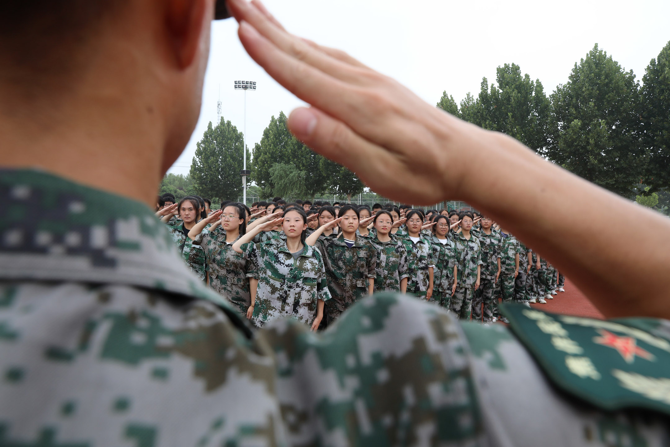 2022年8月14日，中国河南，一名教官在在军事训练中教高中新生行军礼。摄：Xu Hongxing/VCG via Getty Images