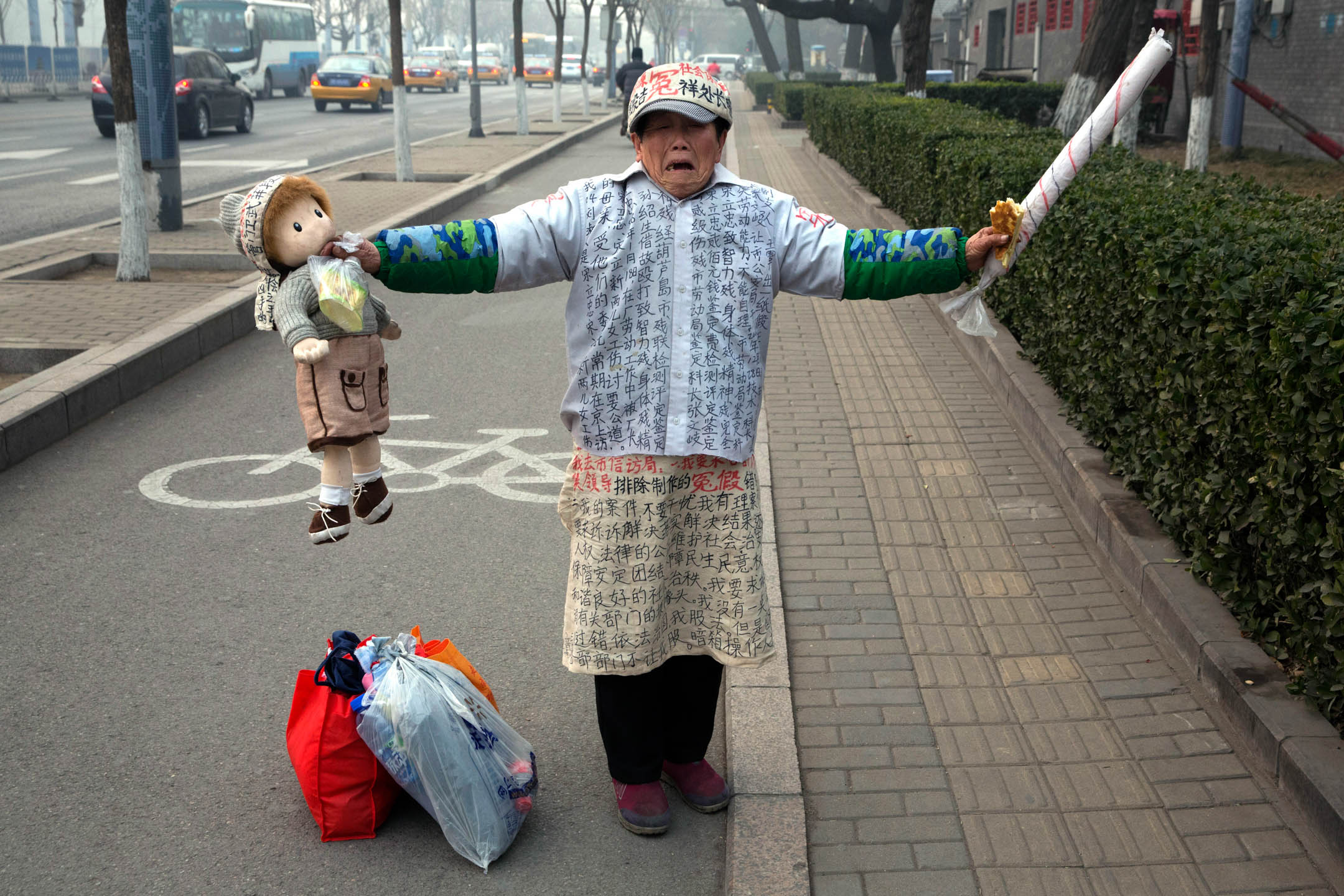 2015年12月22日，中国北京，一名男士身穿写满抗议字句的衣服站在街道上。摄：Ng Han Guan/AP/达志影像