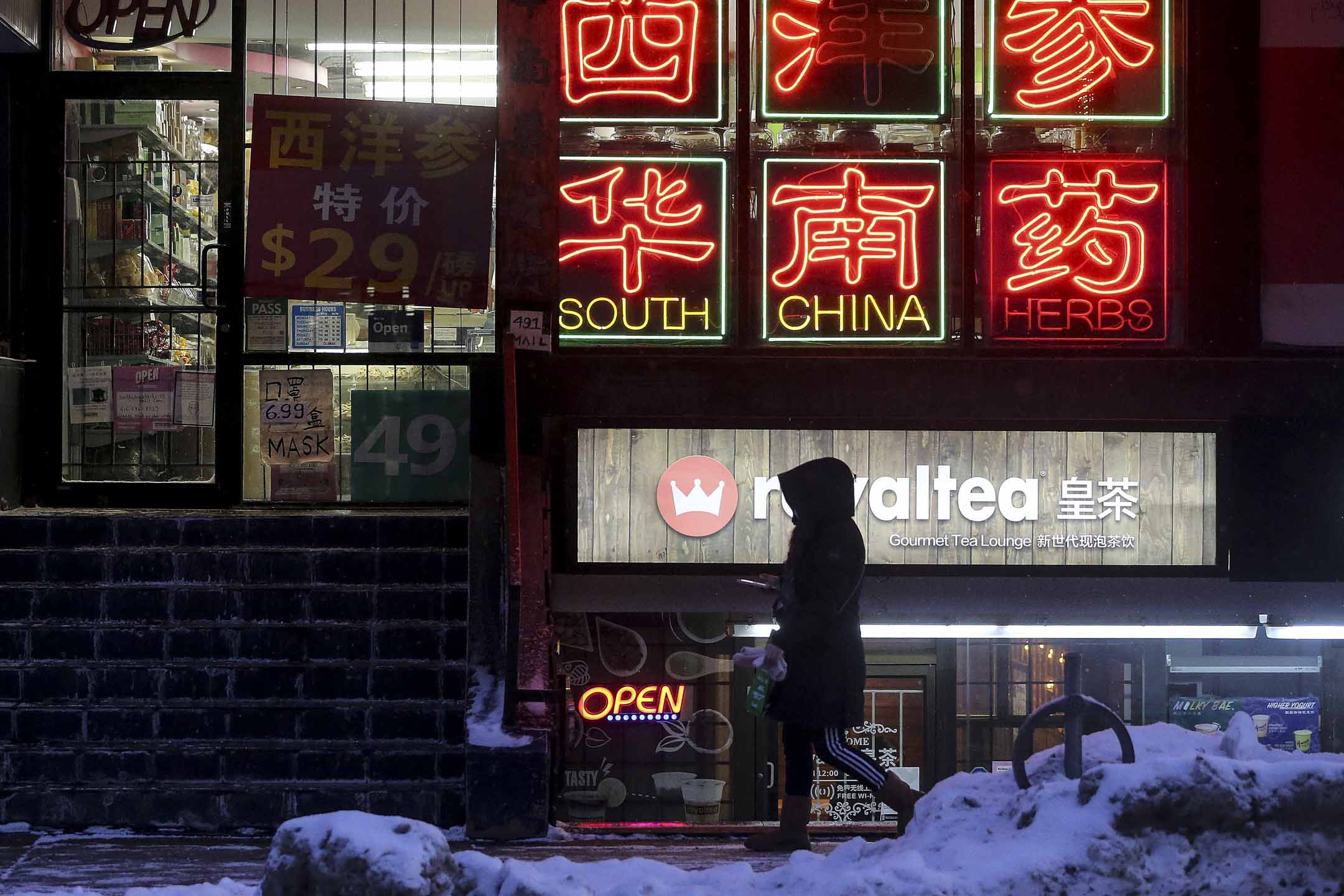 多伦多唐人街晚上一位女士在商店前经过。摄：Steve Russell/Toronto Star via Getty Images