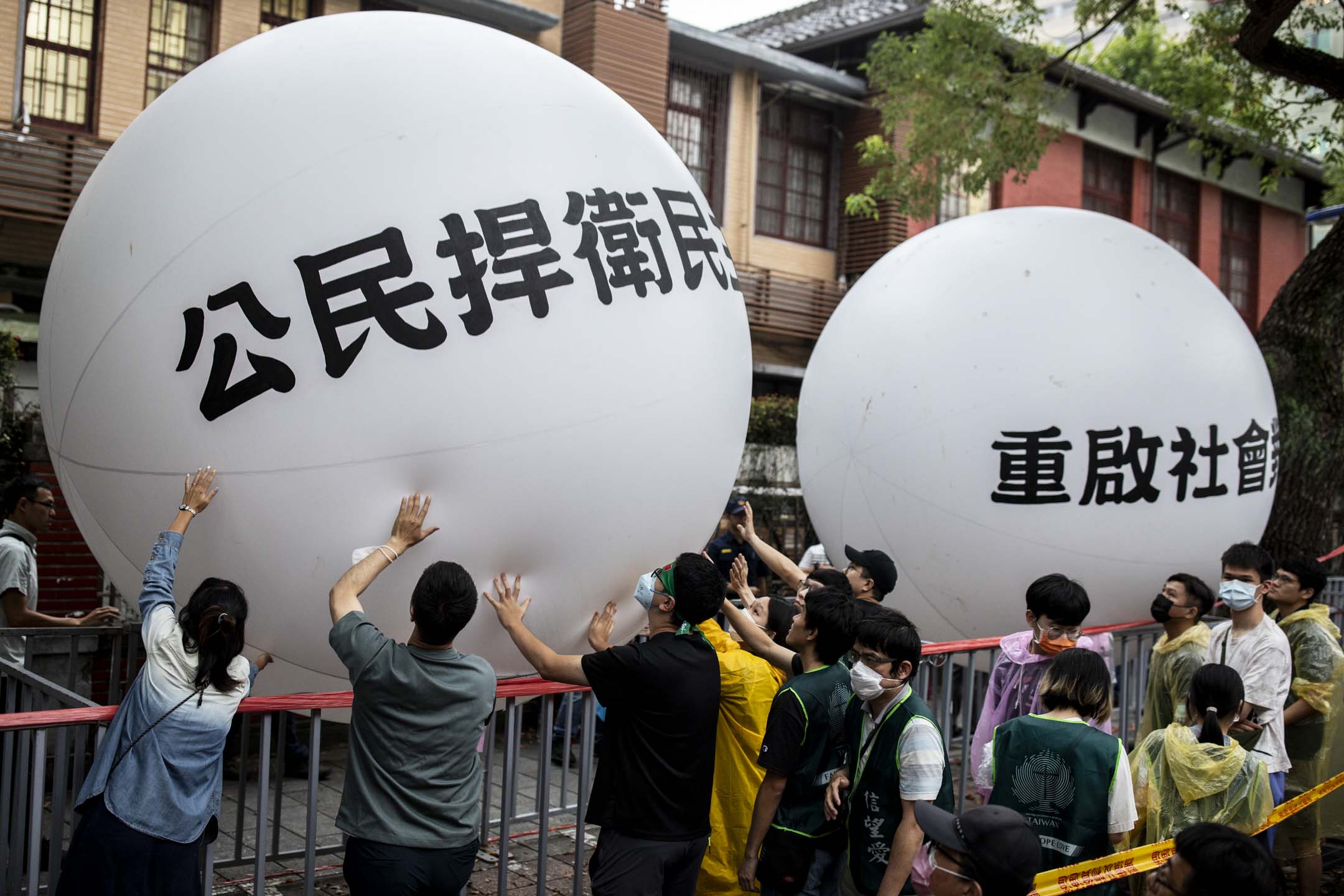 2024年5月28日，台北，立法院進行國會改革法案審議，立法院外有民衆集會，抗議民眾把寫著「公民捍衛民主」、「重啟社會對話」的大型氣球，接力傳遞到立法院前，表達這次行動訴求。攝：林振東/端傳媒