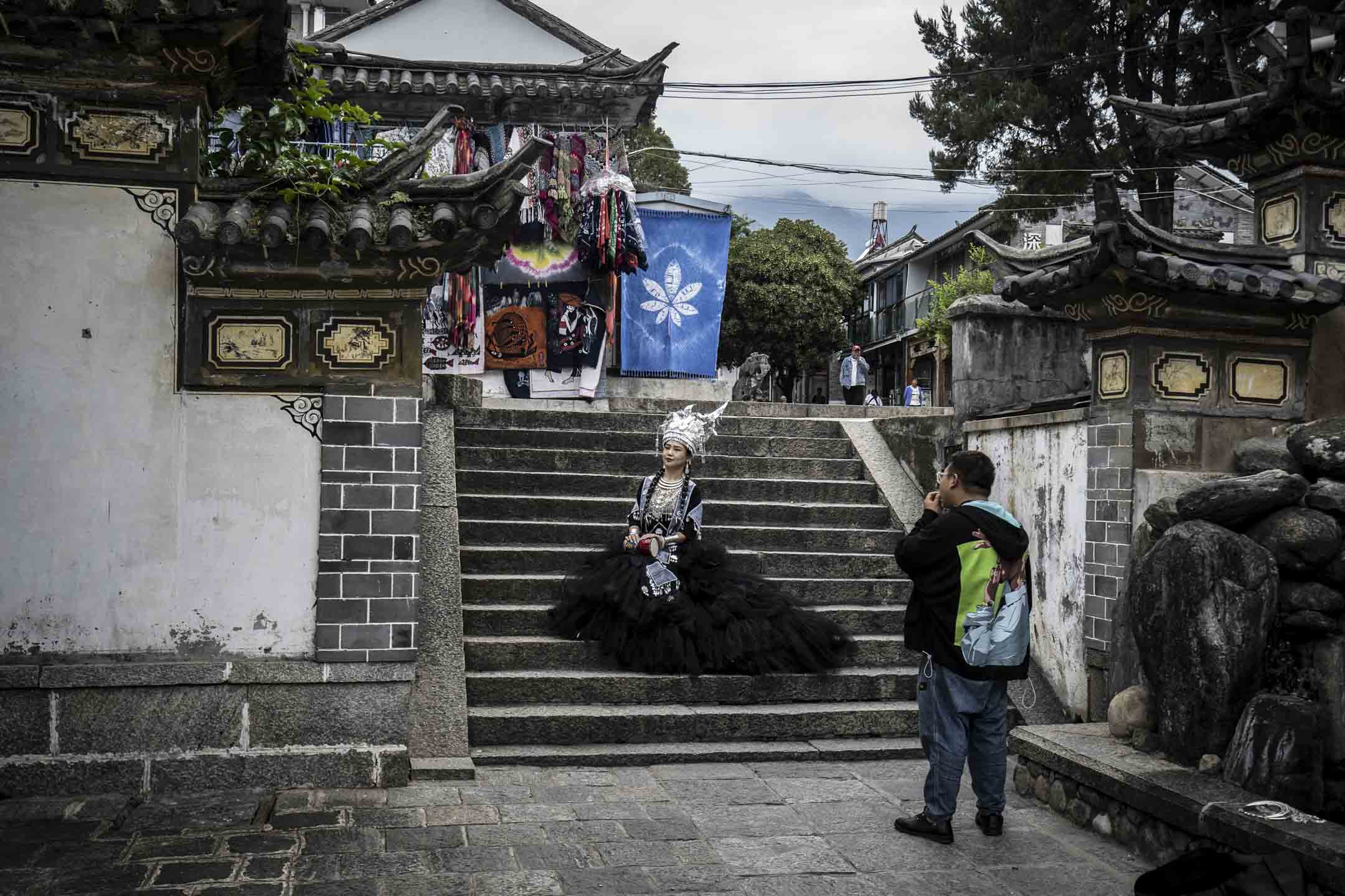 2022年9月6日，中国云南大理，一名身著各种少数民族服饰的游客在摆姿势拍照。摄：Qilai Shen/Bloomberg via Getty Images