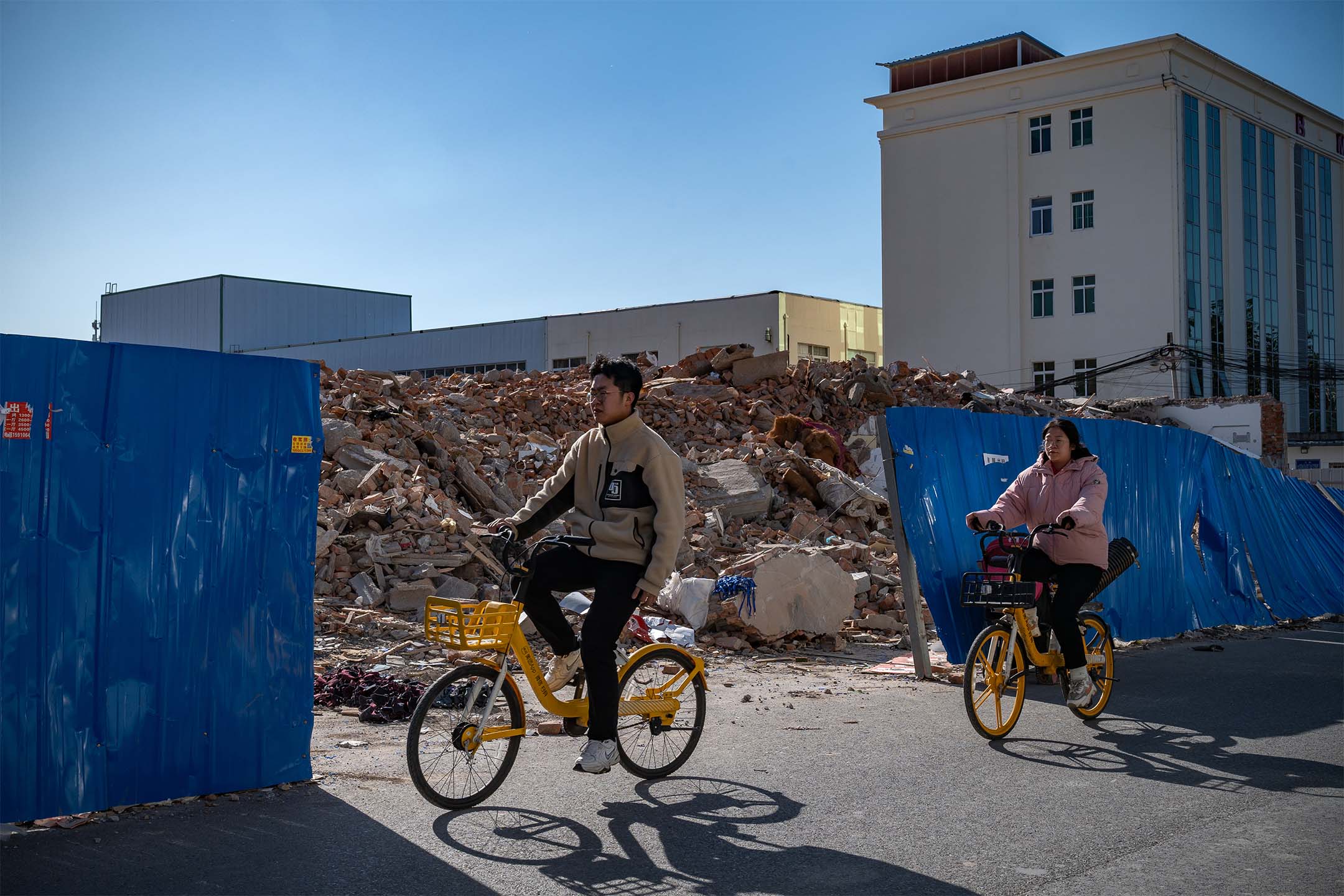 2023年11月17日，中国北京，人们骑单车经过被拆除的建筑物。摄：Andrea Verdelli/Bloomberg via Getty Images