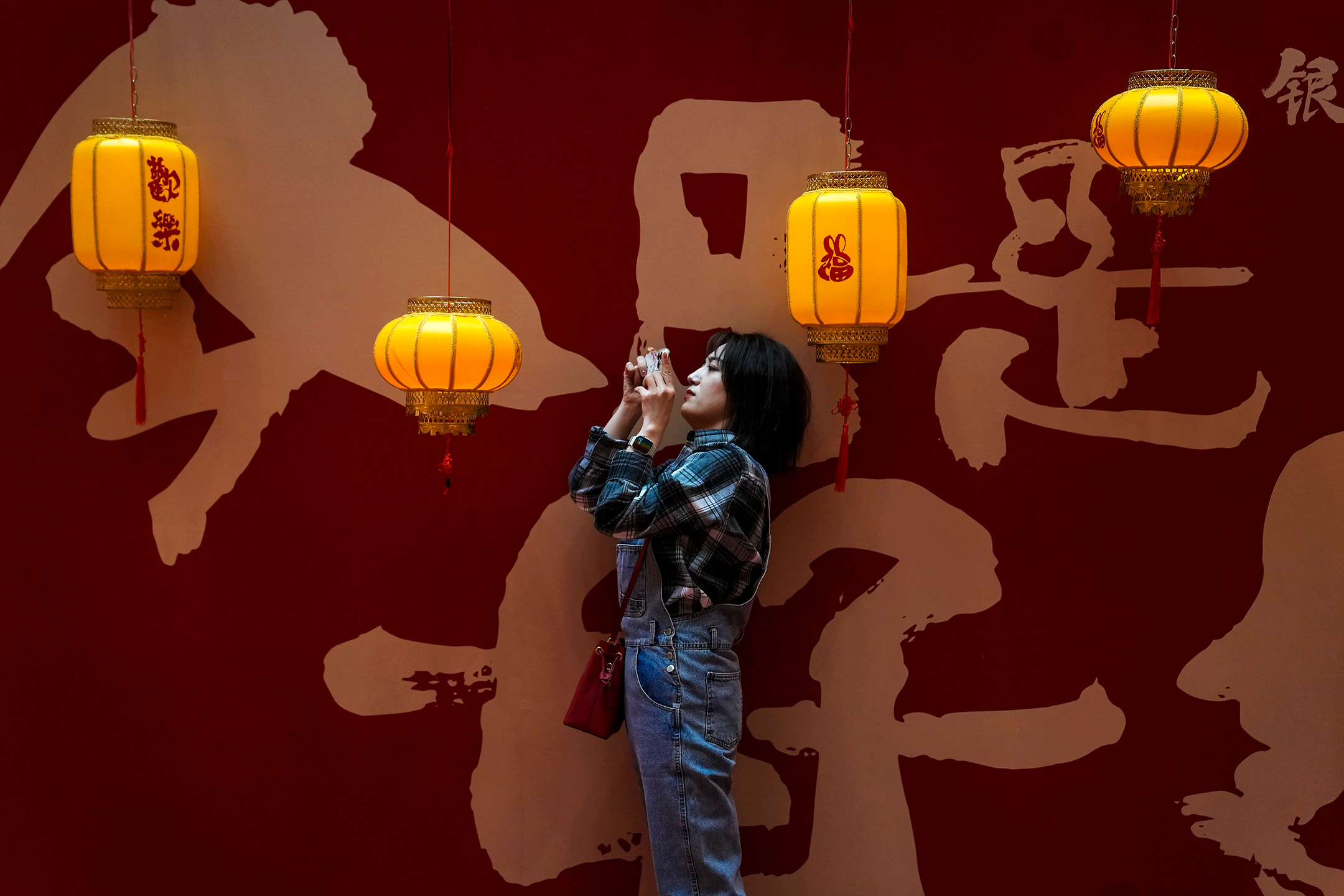 2023年2月5日，中国北京，一名女子在购物中心内拍摄灯笼。摄：Andy Wong/AP/达志影像