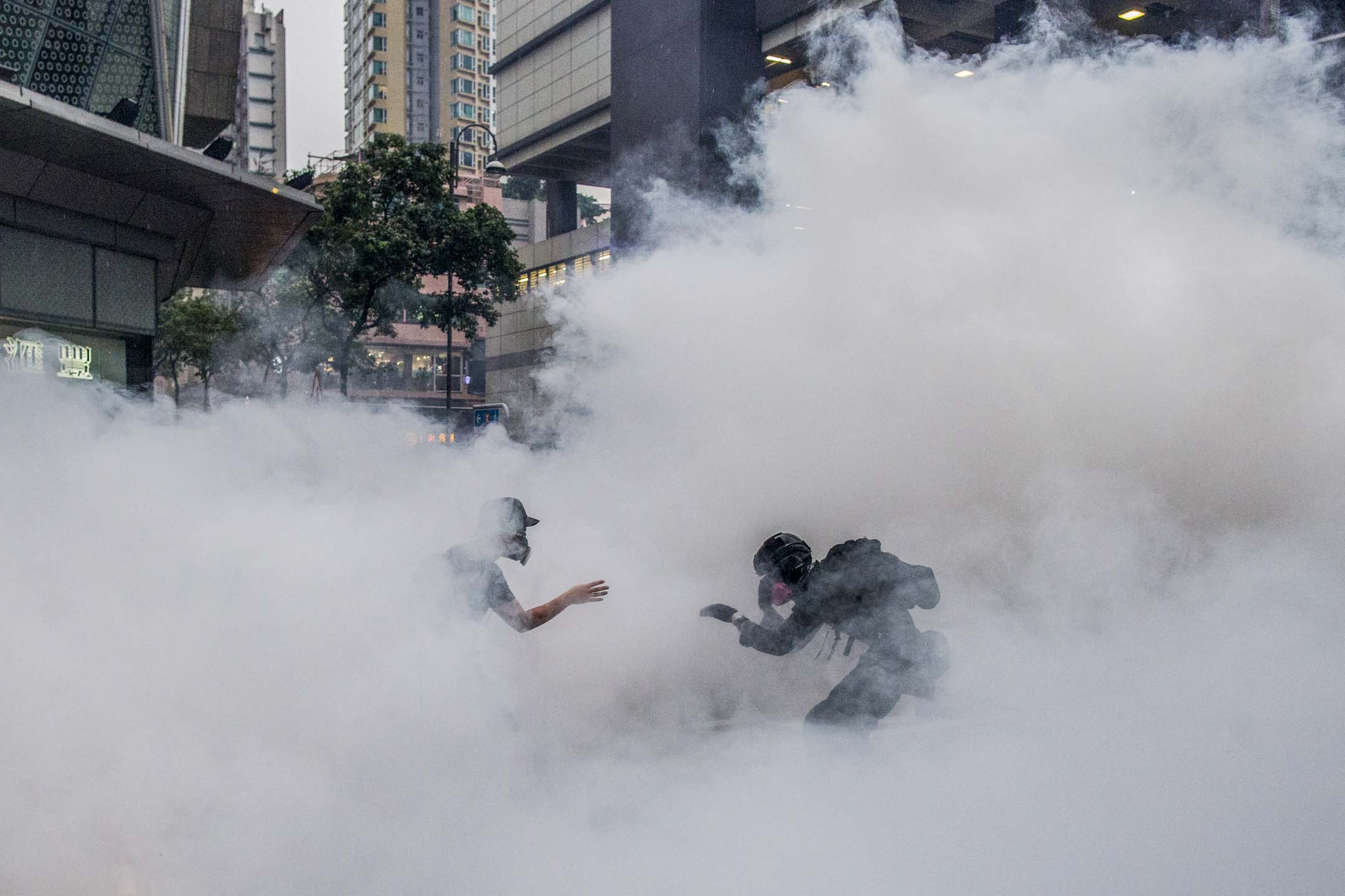 2019年8月25日，荃灣，防暴警察施放催淚彈，在濃煙中的反修例運動示威者。 攝：林振東/端傳媒