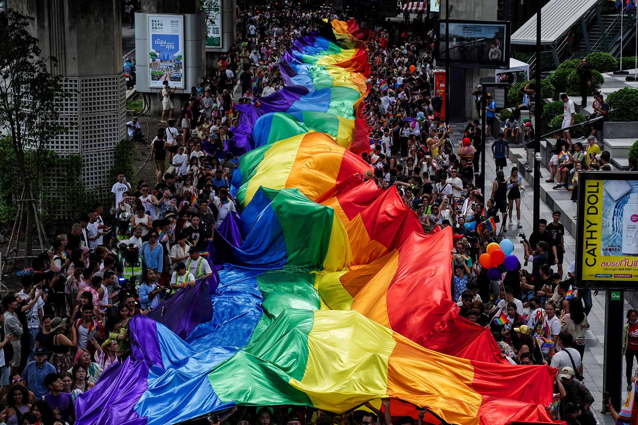 2024年6月1日，泰国曼谷，人们举著一面巨大的彩虹旗参加 LGBTQ+ 游行，纪念骄傲月庆祝活动。摄：Anusak Laowilas/NurPhoto via Getty Images