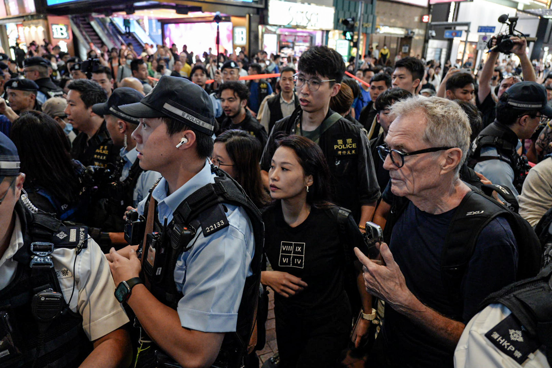 2024年6月4日，一名女士身穿印有罗马数字的衣服，被警方包围后带上警车。摄：Ryan Lai/端传媒