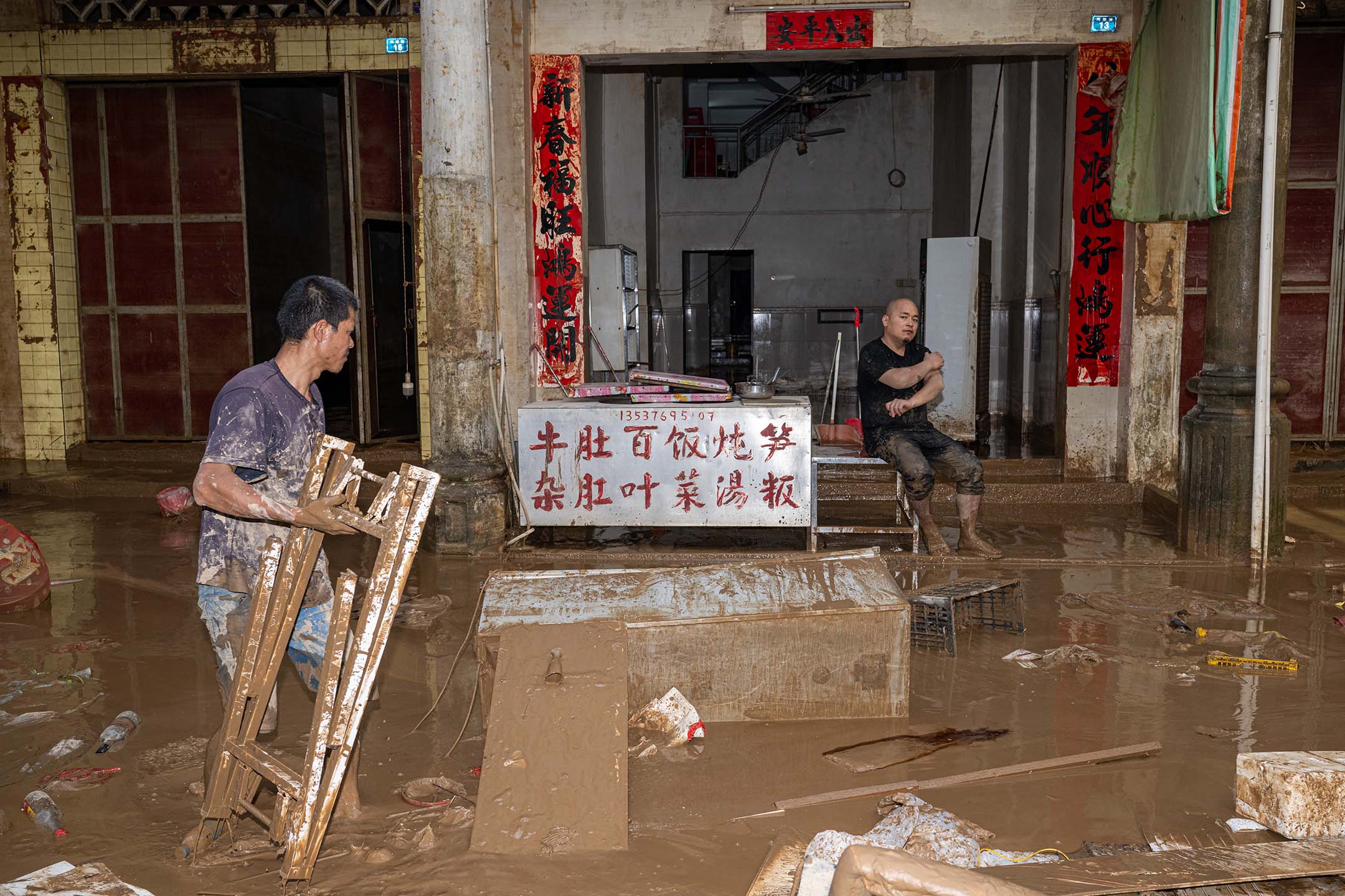 2024年6月19日，中国梅州，暴雨引发洪水，村民清理垃圾。摄：John Ricky/Anadolu via Getty Images