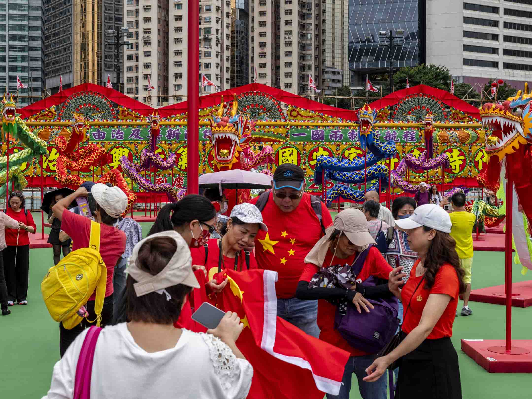 2023年6月30日，维园“庆祝香港回归祖国二十六周年”庆祝活动，现场有本地特色大型花牌配合26条传统舞龙，市民带同国旗拍照。摄：林振东/端传媒