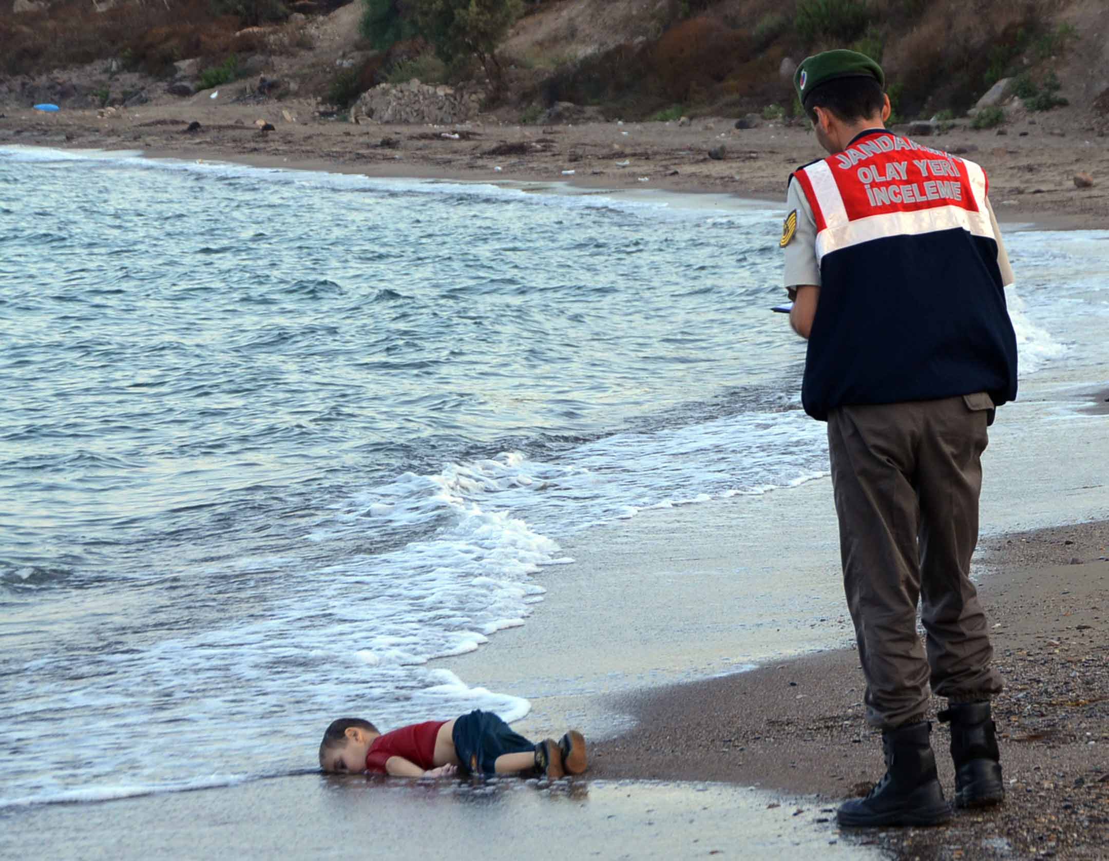 2015年9月2日，叙利亚三岁男孩 Aylan Kurdi 于地中海溺亡后，伏尸土耳其海滩。 照片成为全球新闻的头条，促使国际认真应对难民危机，欧洲国家暂时对难民采取较开放态度。摄：Nilufer Demir/DHA via AP/达志影像