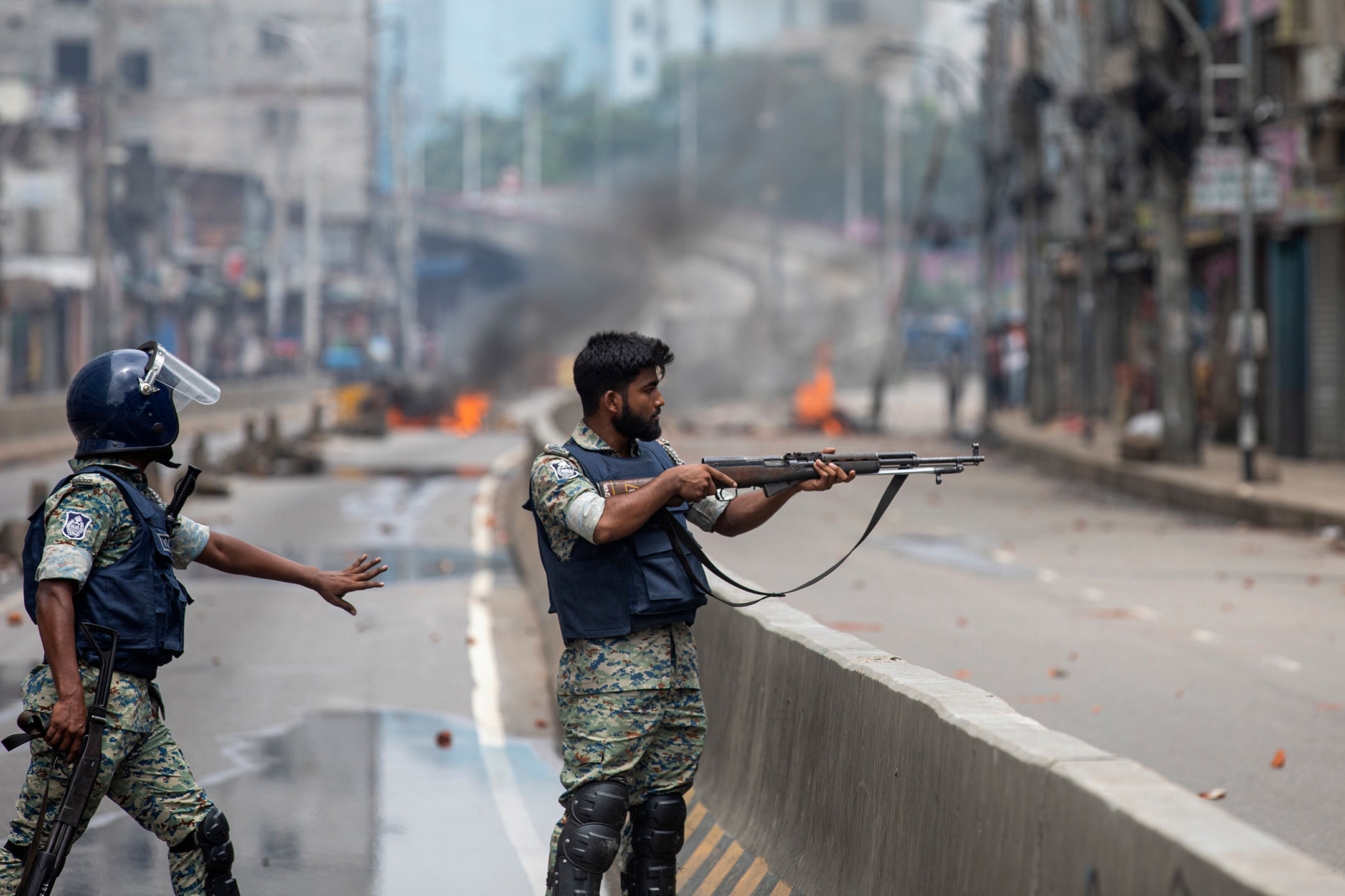 2024年8月5日，孟加拉，一名警察将武器瞄准示威者。摄：Rajib Dhar/AP/达志影像