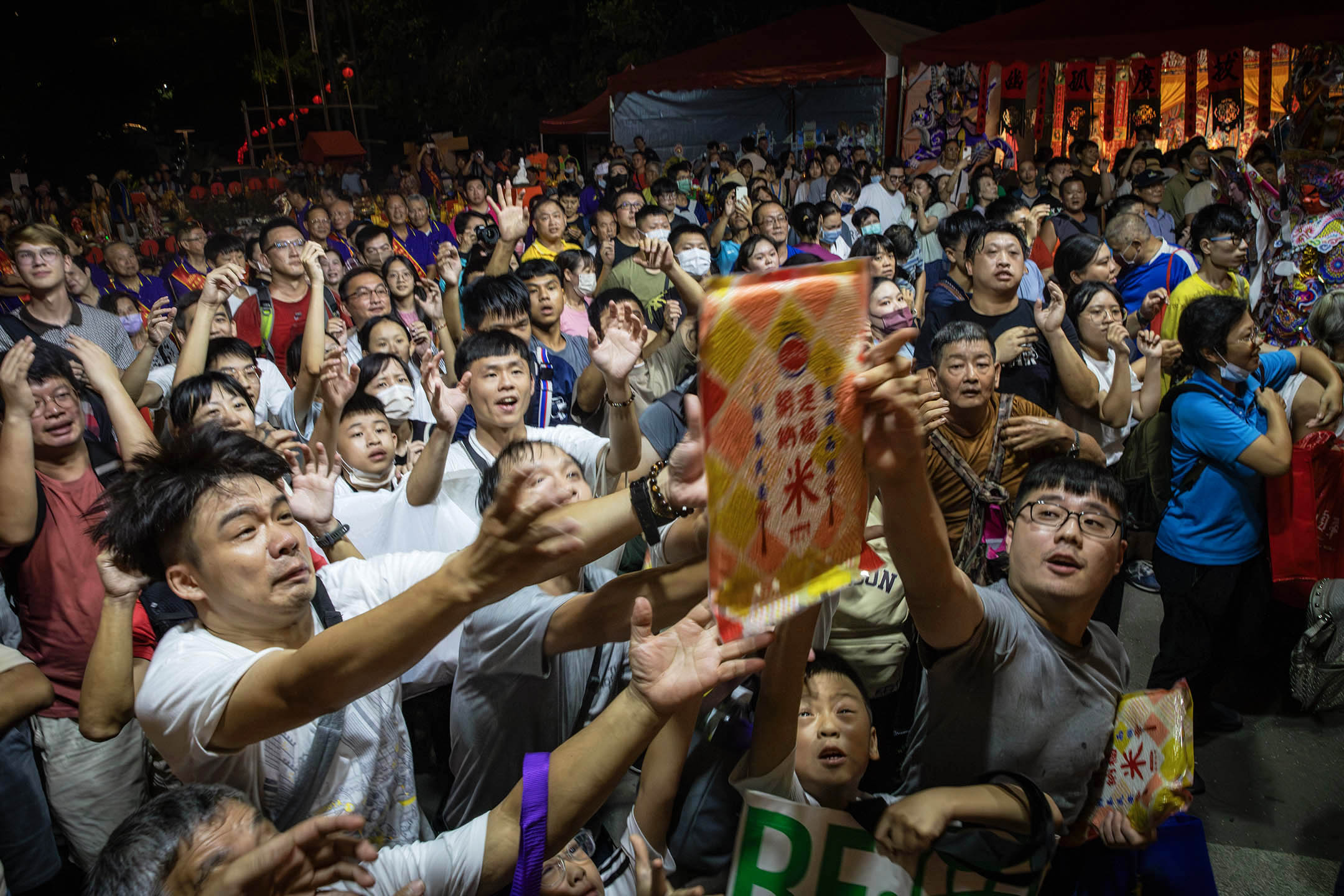 2024年8月18日，鸡笼中元祭，人们在争夺由祭坛丢下来的供品。摄：陈焯煇/端传媒