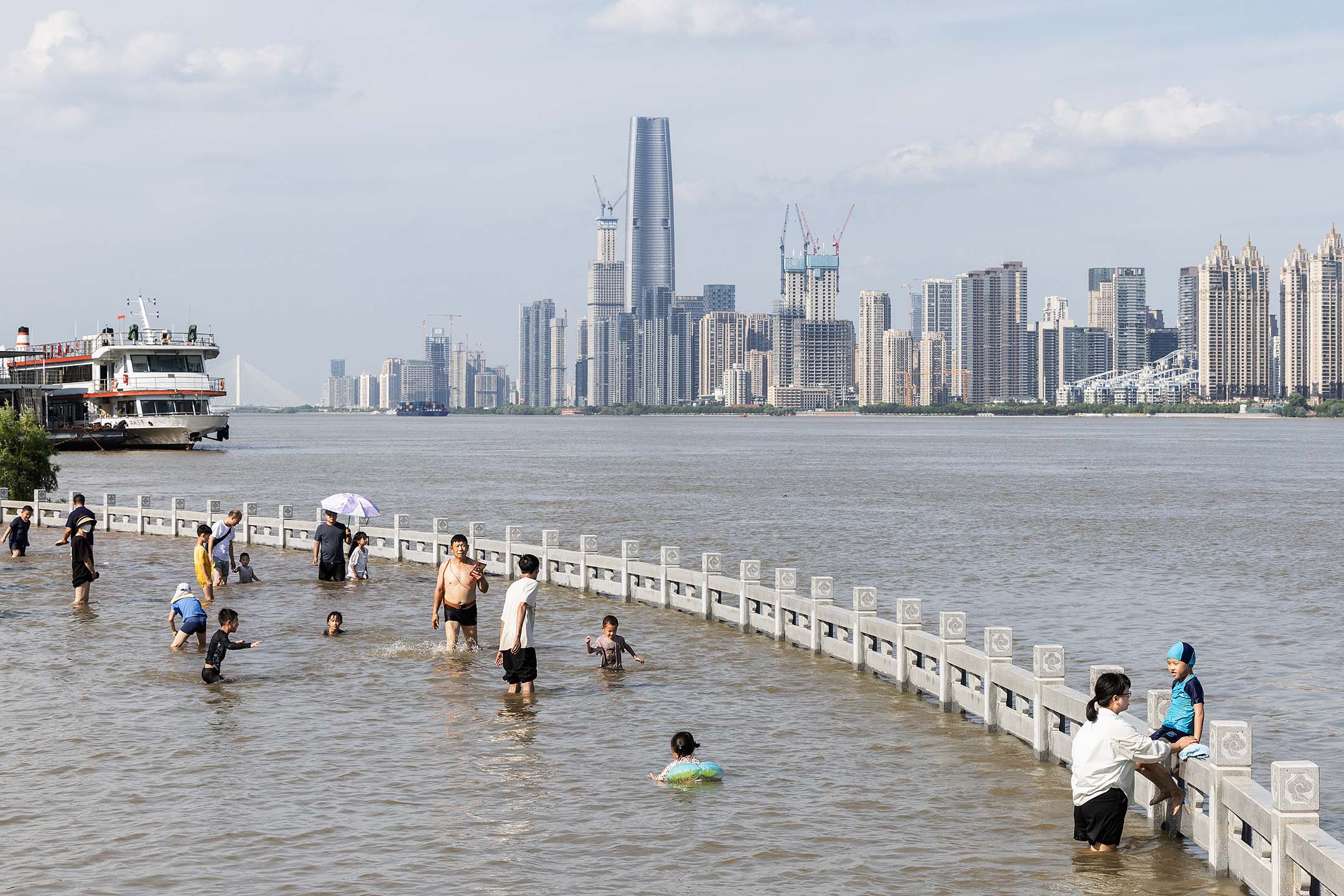 2024年7月7日，中国武汉，人们经过被洪水淹没的长江汉口江岸公园。摄：Ren Yong/SOPA Images/LightRocket via Getty Images